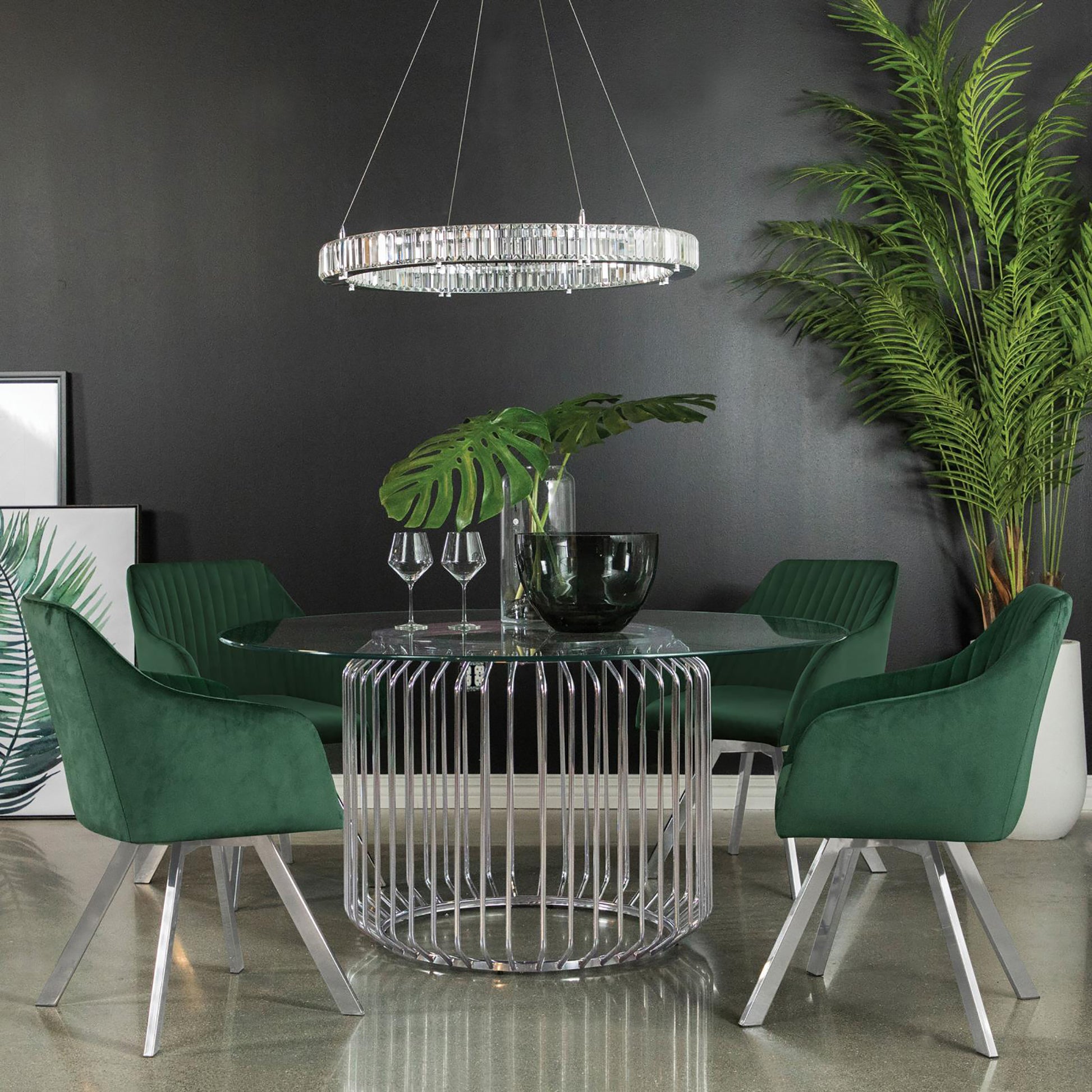 Emerald green velvet dining chairs with brushed metal legs around a clear glass table