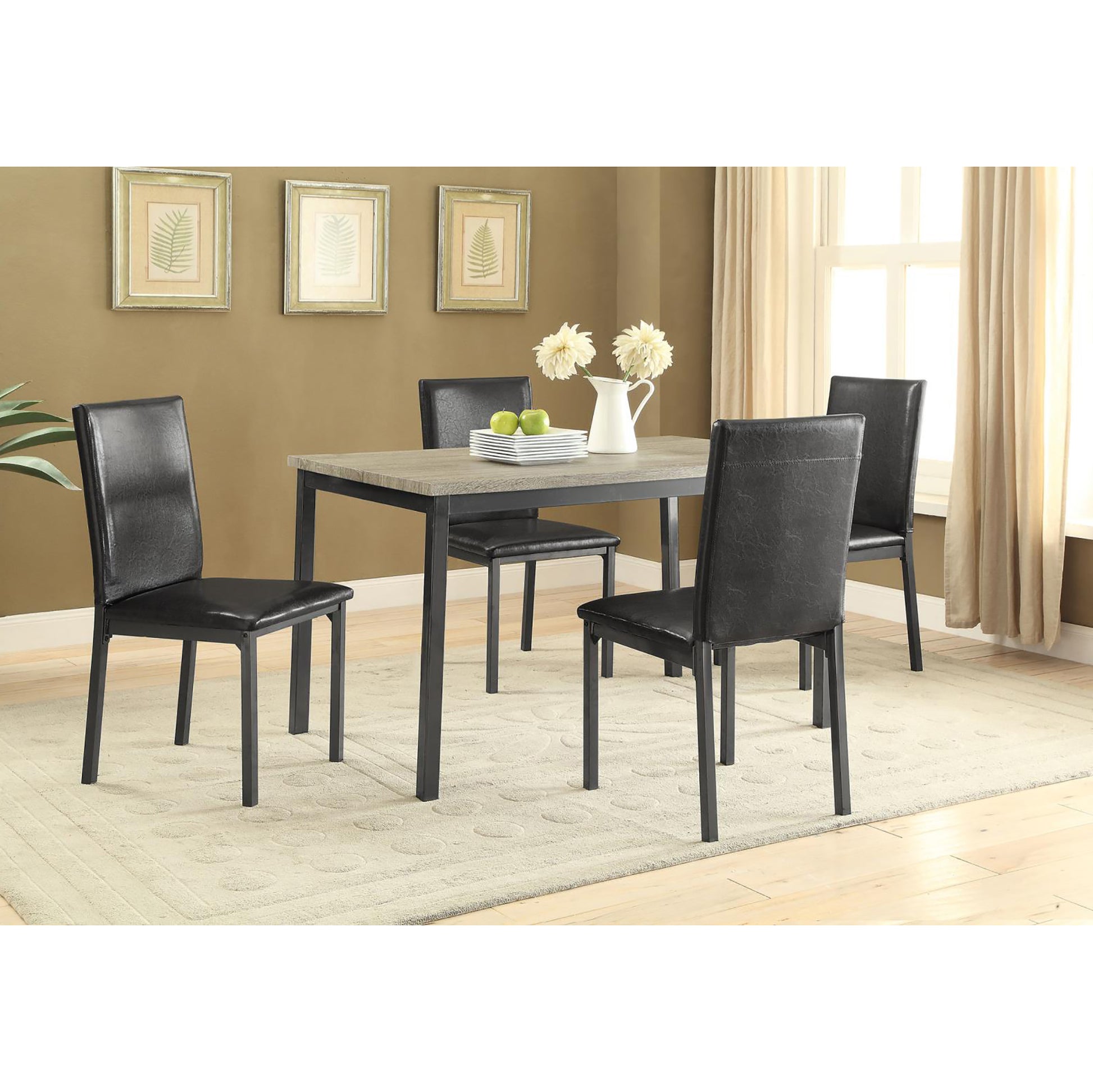 Four black faux leather dining chairs with metal frames around a light woodgrain table