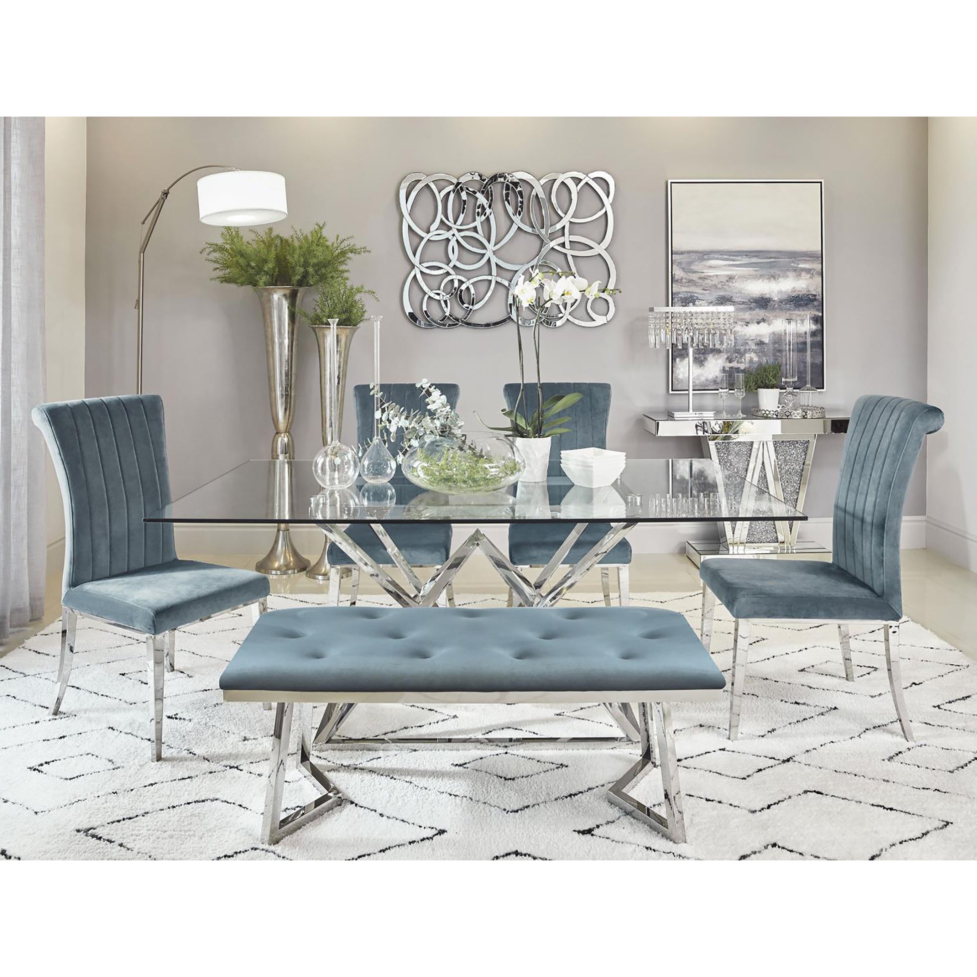 Glass top dining table with chrome base and plush teal chairs