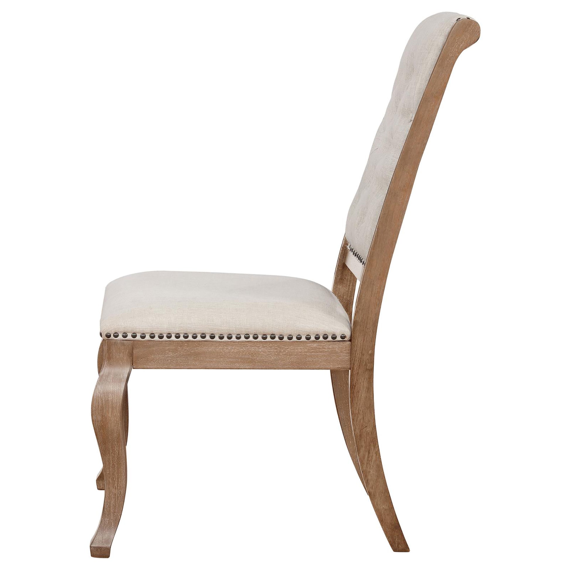 Side view of beige linen upholstered dining chair with nailhead trim and carved wooden legs
