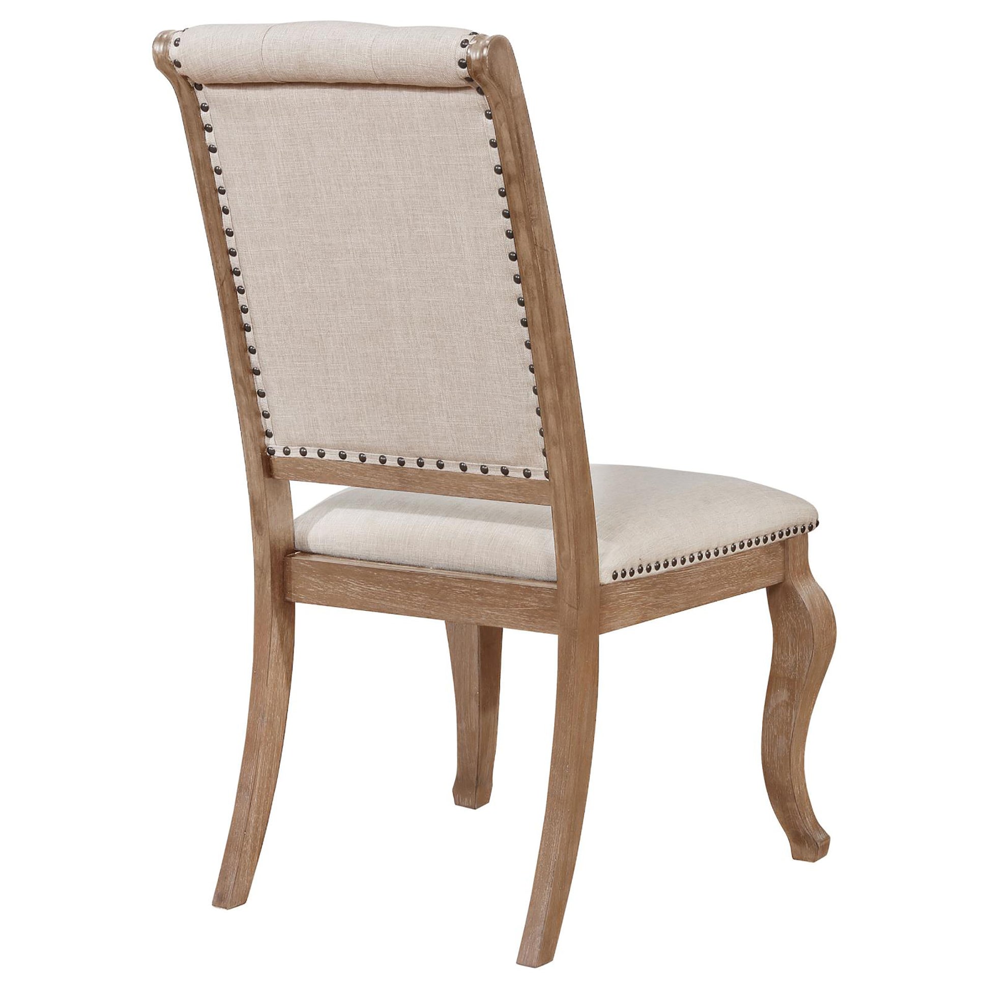 Beige upholstered dining chair with nailhead trim and carved wooden legs