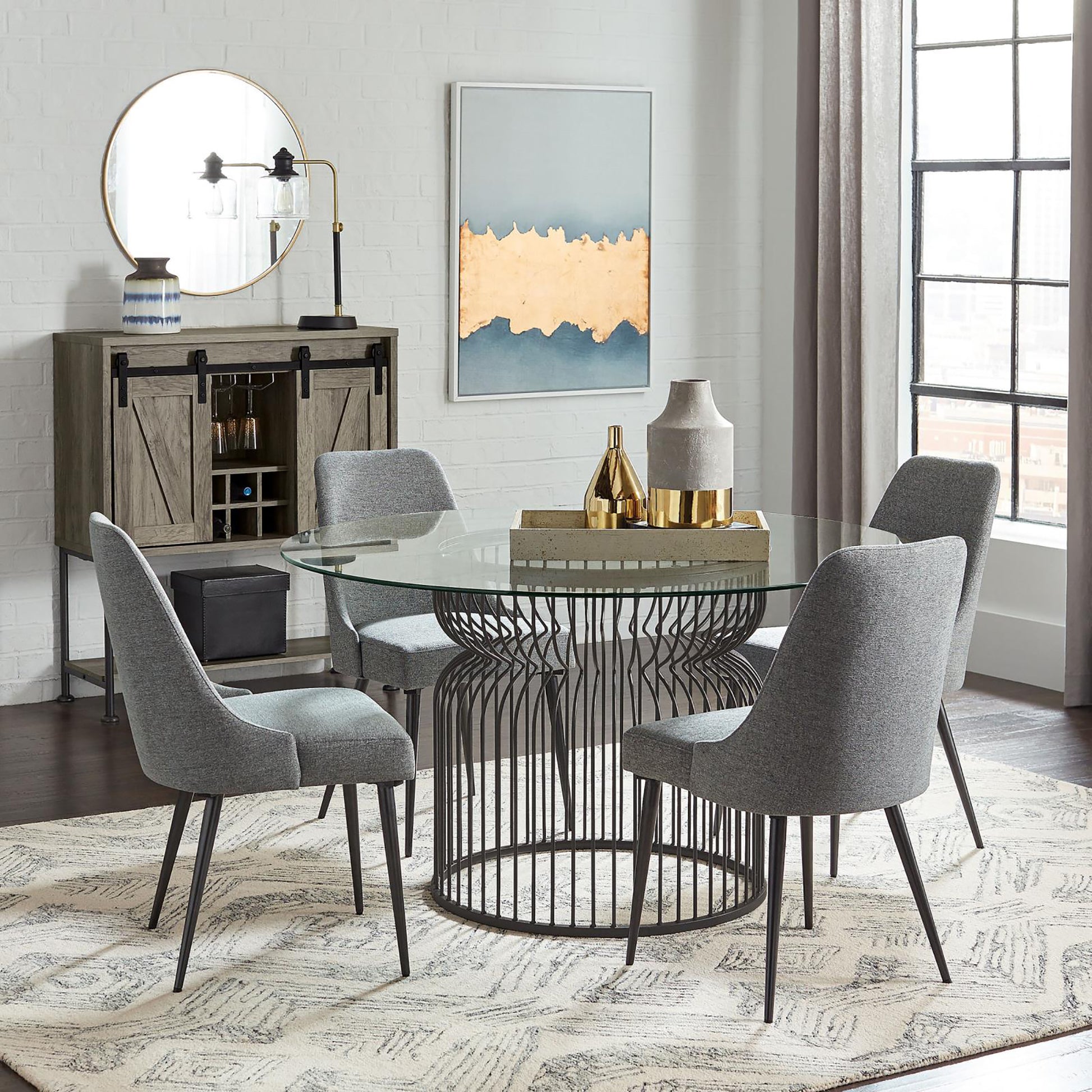 Round glass dining table with four grey upholstered chairs and unique black metal base