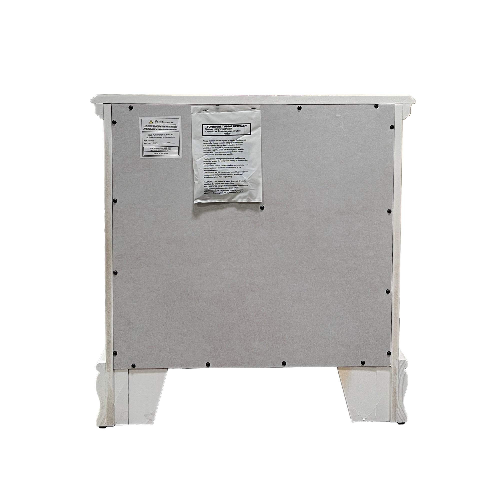 Back panel of a white distressed nightstand with ornate legs and two warning labels