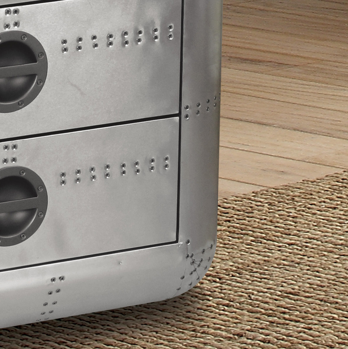 Closeup of a silver industrial dresser with riveted accents and two circular pulls
