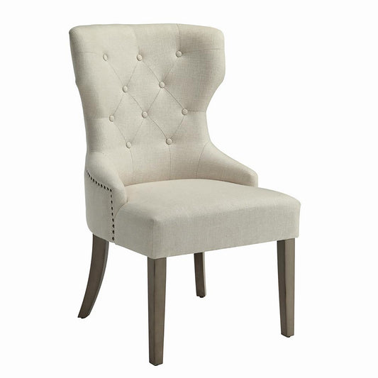 Tufted linen dining chair in natural beige with nailhead trim accents and dark wood legs