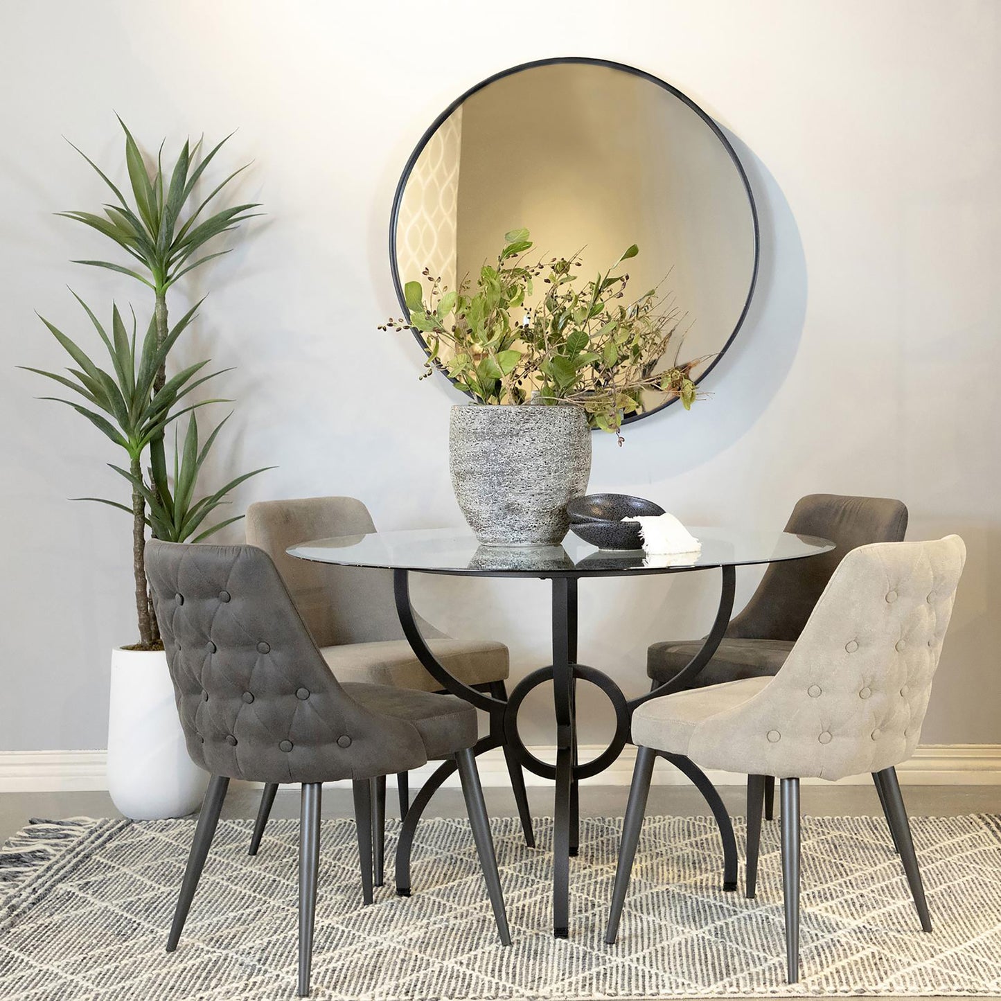 Elegant glass top dining table with four tufted velvet chairs and faux plant