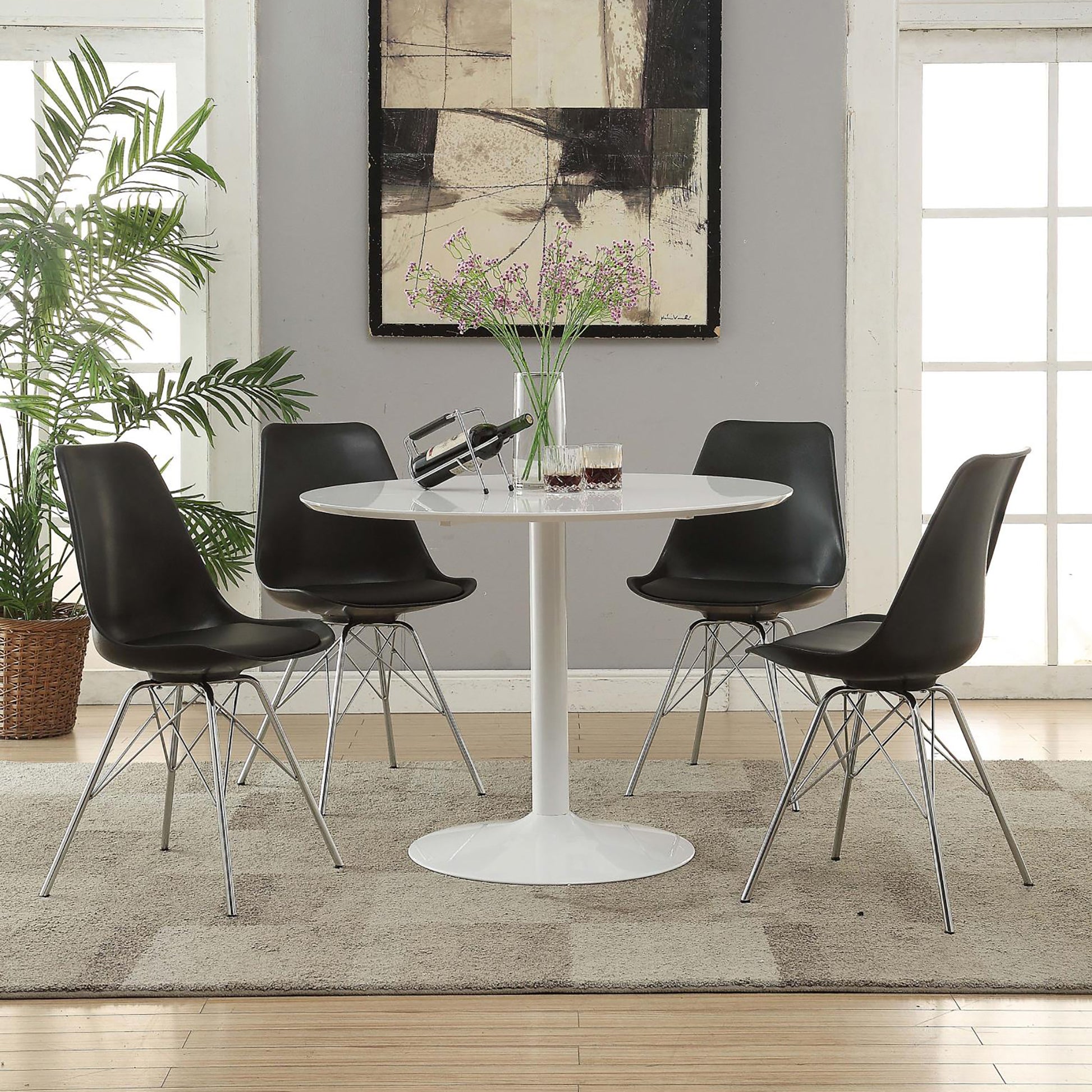 Four black modern dining chairs with chrome legs surround a white pedestal dining table