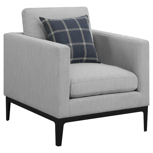 Grey fabric armchair with dark plaid accent pillow and tapered legs