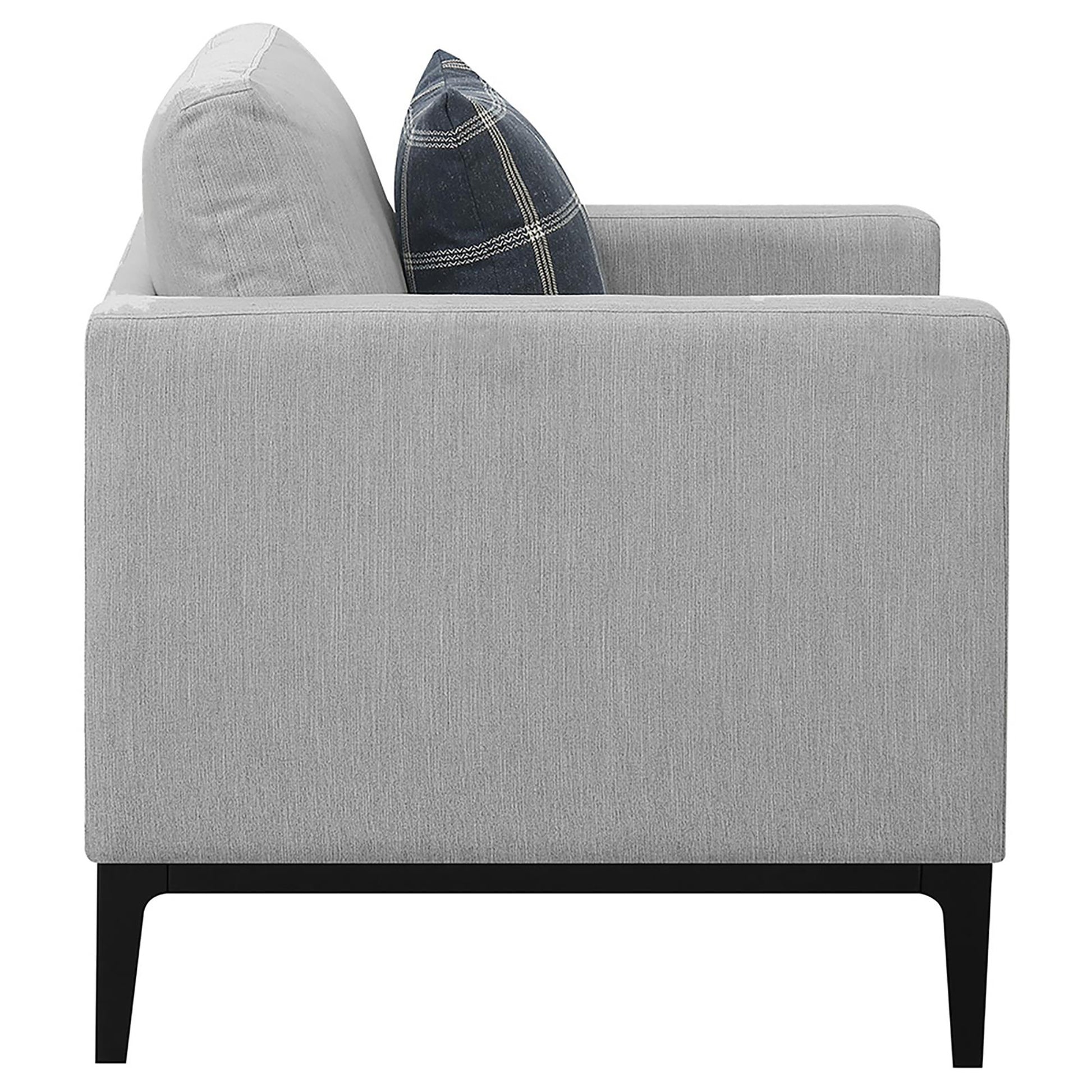 Modern gray fabric sofa with a dark plaid accent pillow and black legs