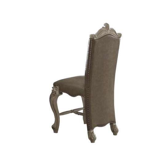 Ornate grey upholstered dining chair with carved wooden legs and silver nailhead trim
