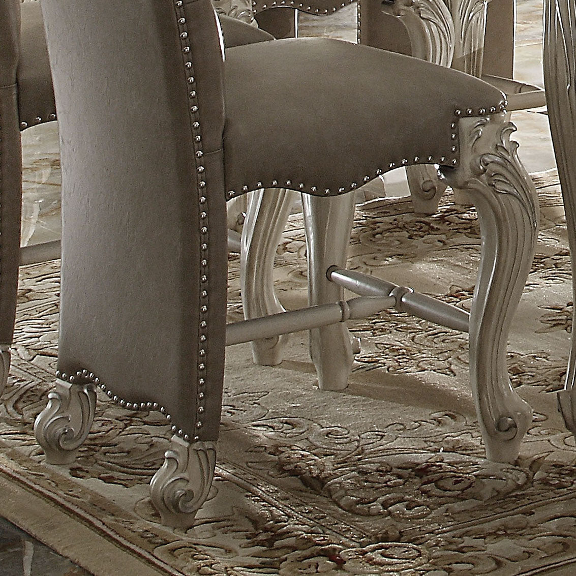 Tufted grey fabric bar stool with silver nailhead trim and ornate carved legs