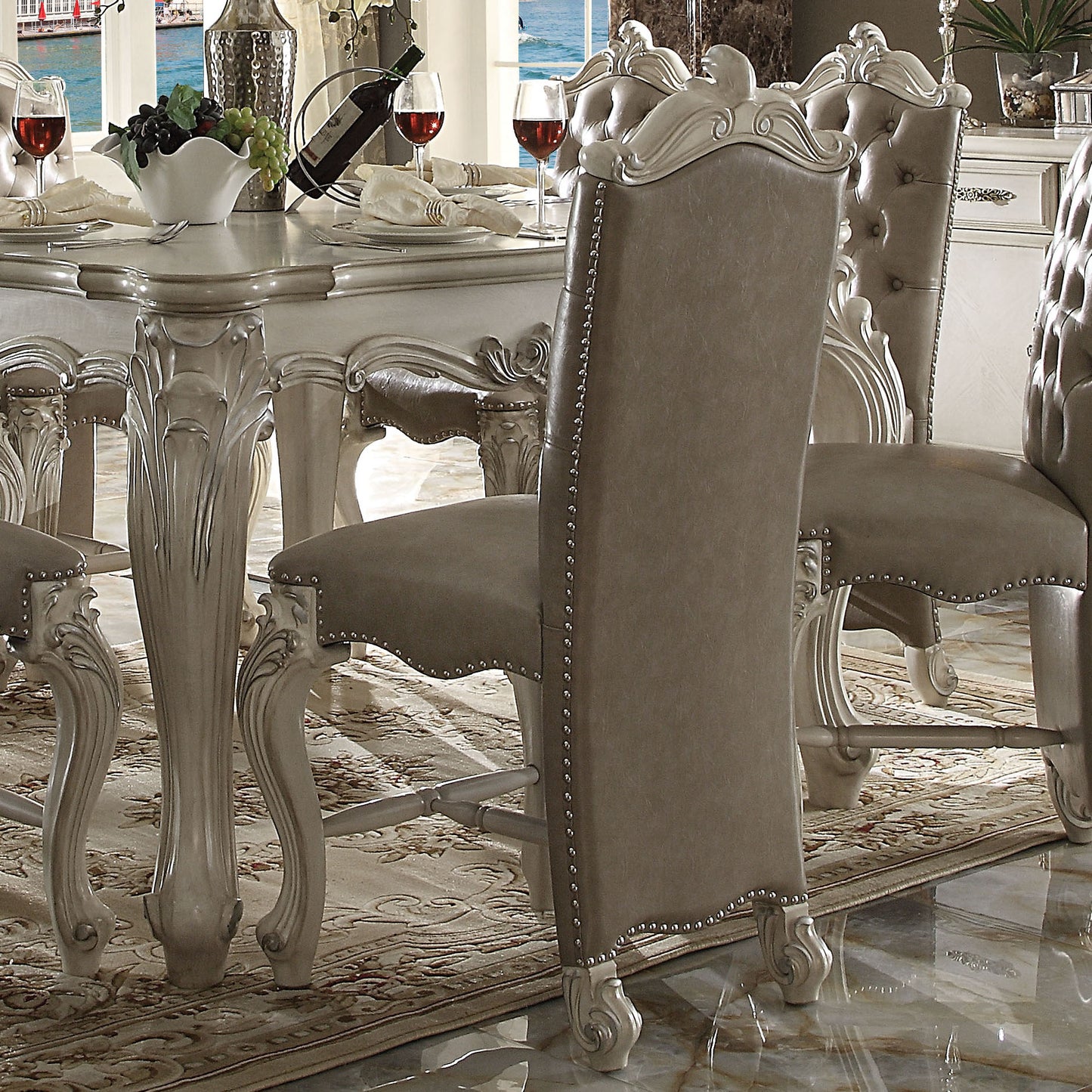 Elegant gray tufted dining chair with silver nailhead trim and carved ornate legs perfect for luxury dining rooms
