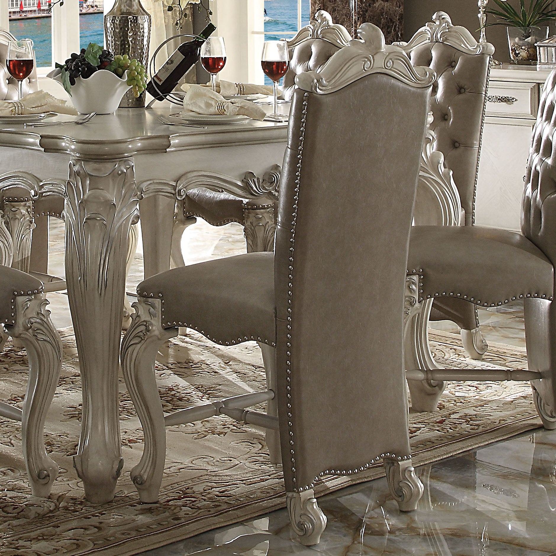 Elegant gray tufted dining chair with silver nailhead trim and carved ornate legs perfect for luxury dining rooms
