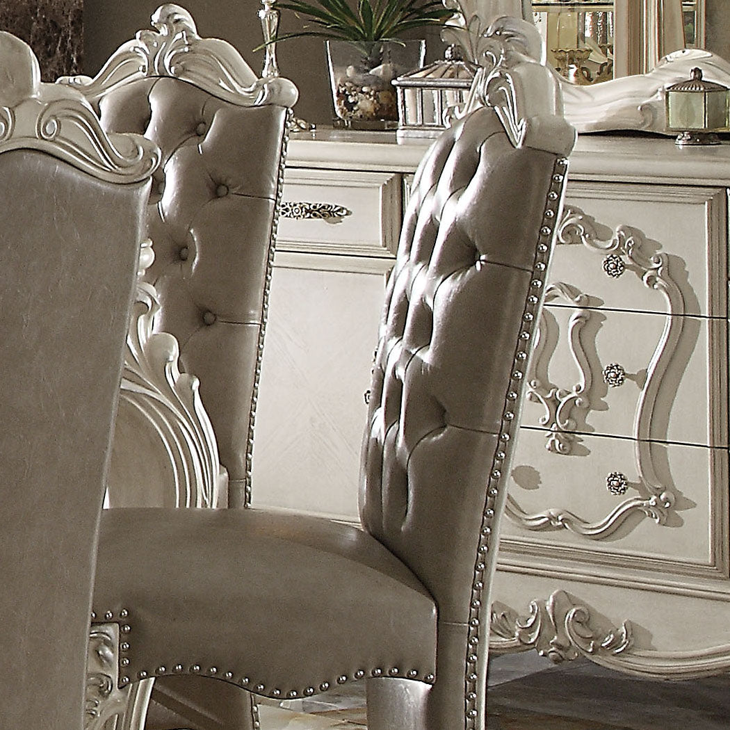 Tufted grey leather dining chair with ornate carved details and nailhead trim