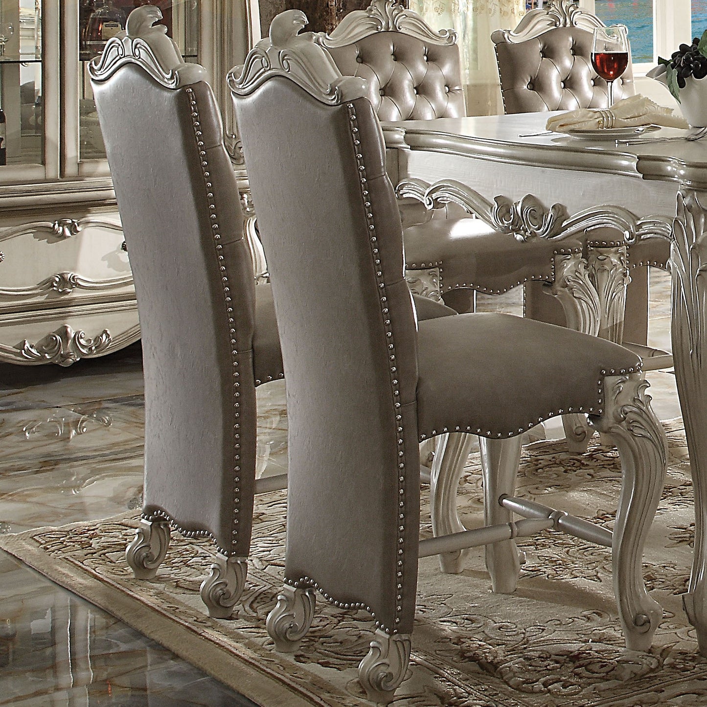 Tufted upholstered dining chair with silver nailhead trim and ornate carved legs