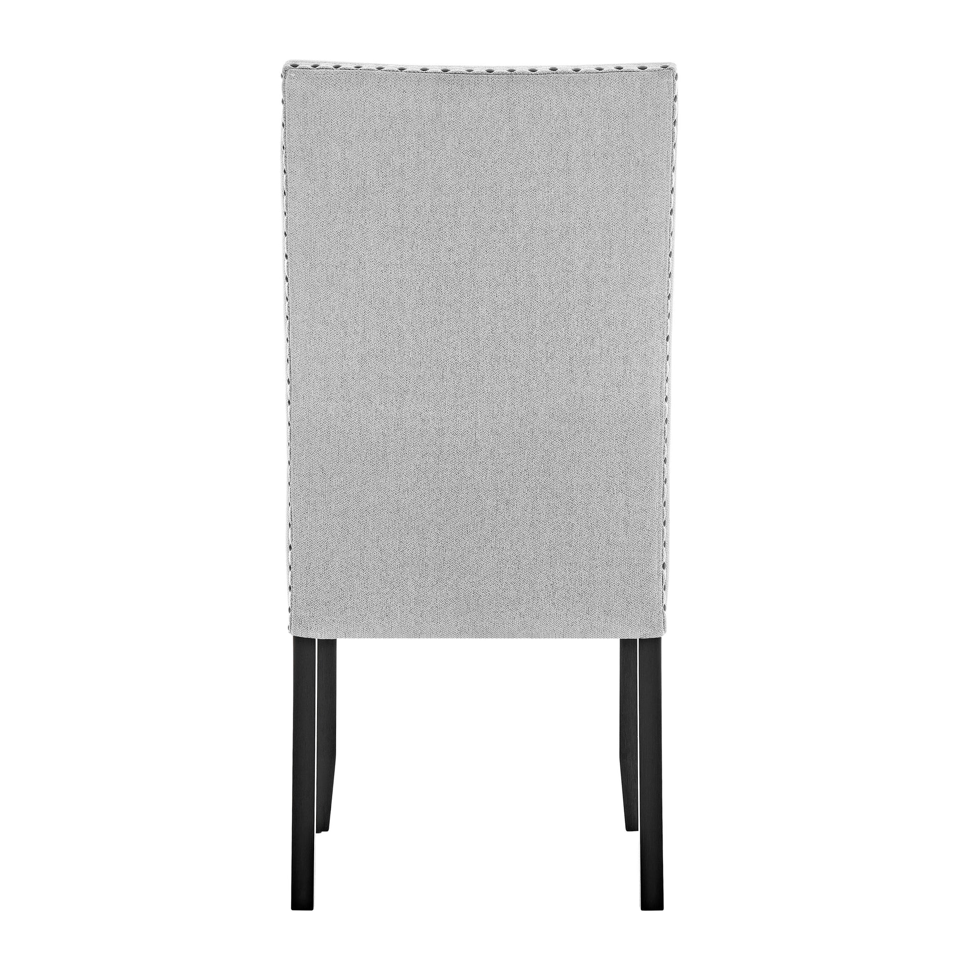 Back view of a grey upholstered dining chair with silver nailhead trim