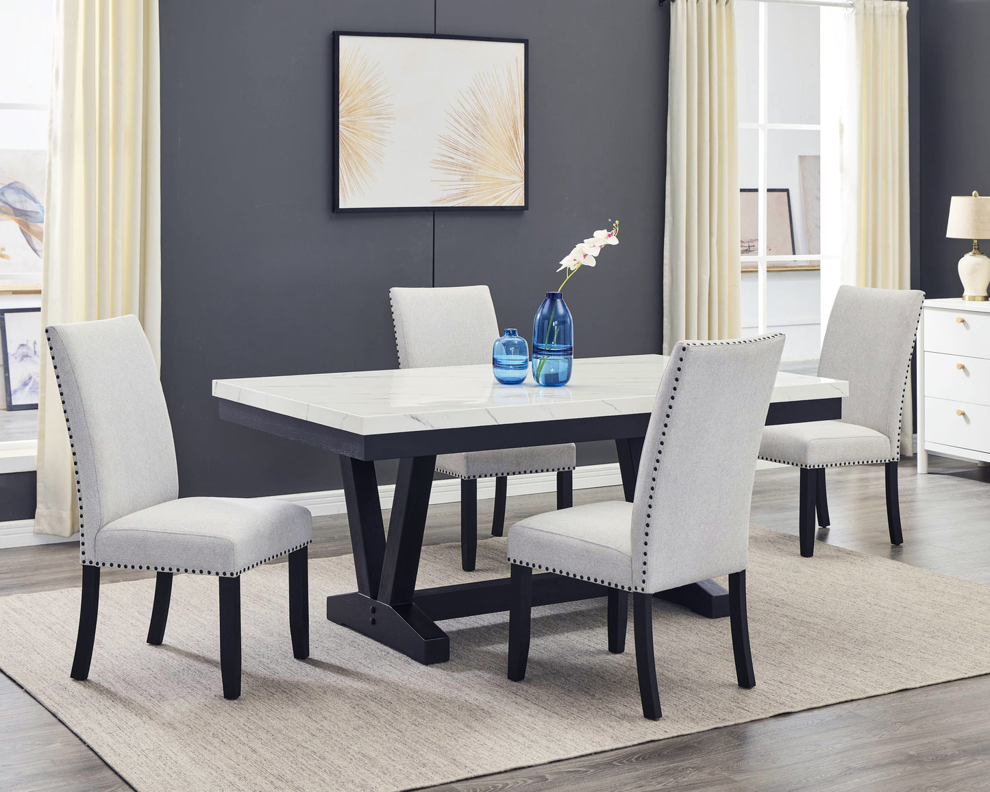 Light gray upholstered dining chairs with nailhead trim around a faux marble top table