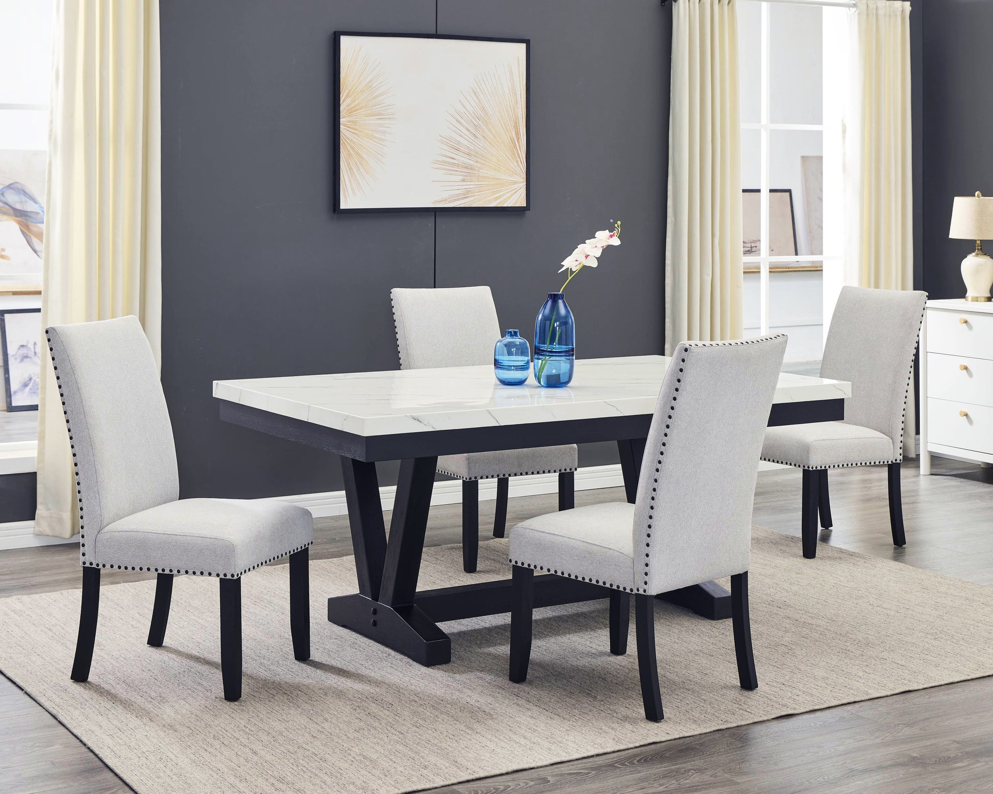 Light gray upholstered dining chairs with nailhead trim around a faux marble top table