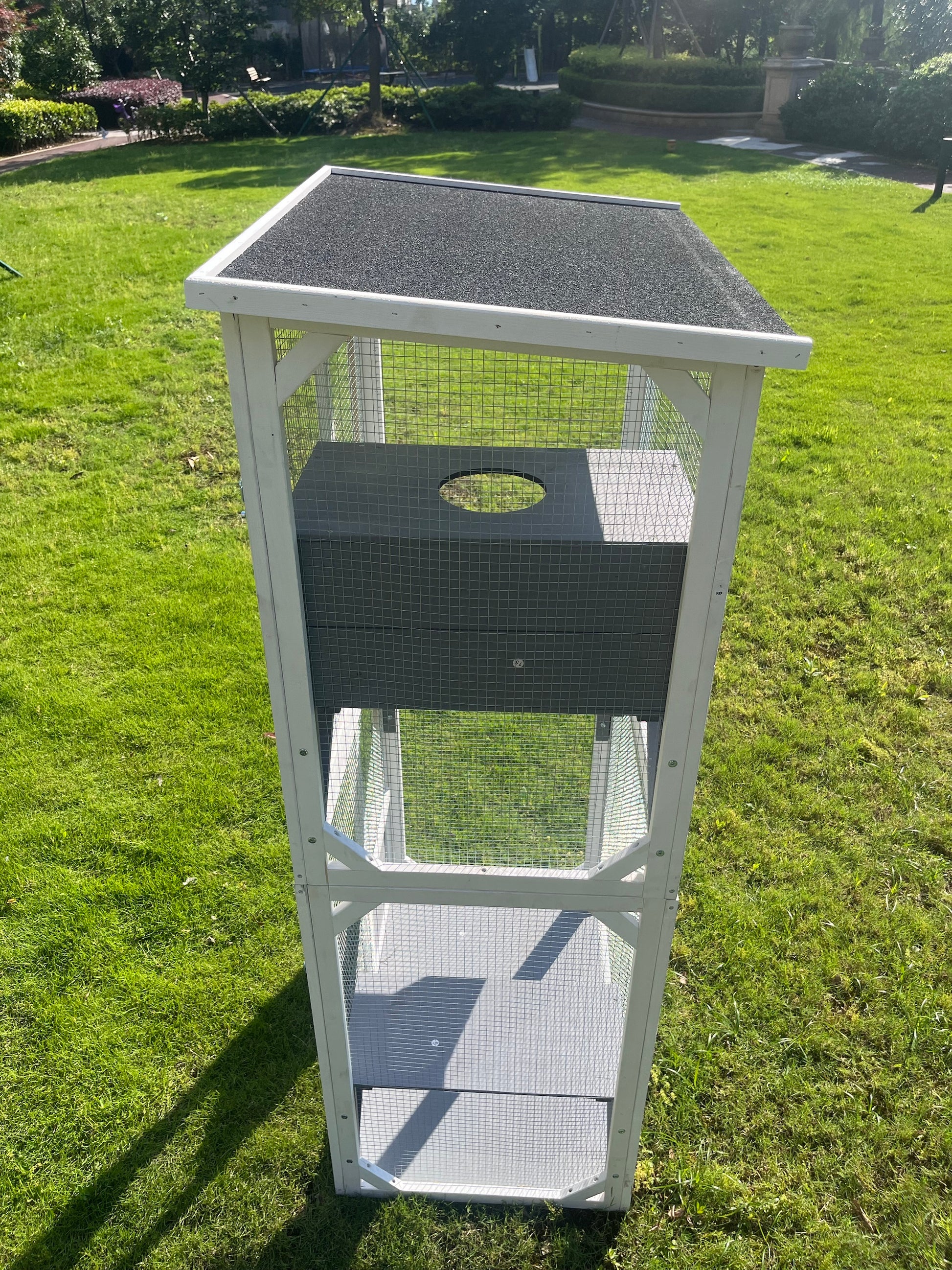 White wooden outdoor cat enclosure with mesh sides and a dark roof