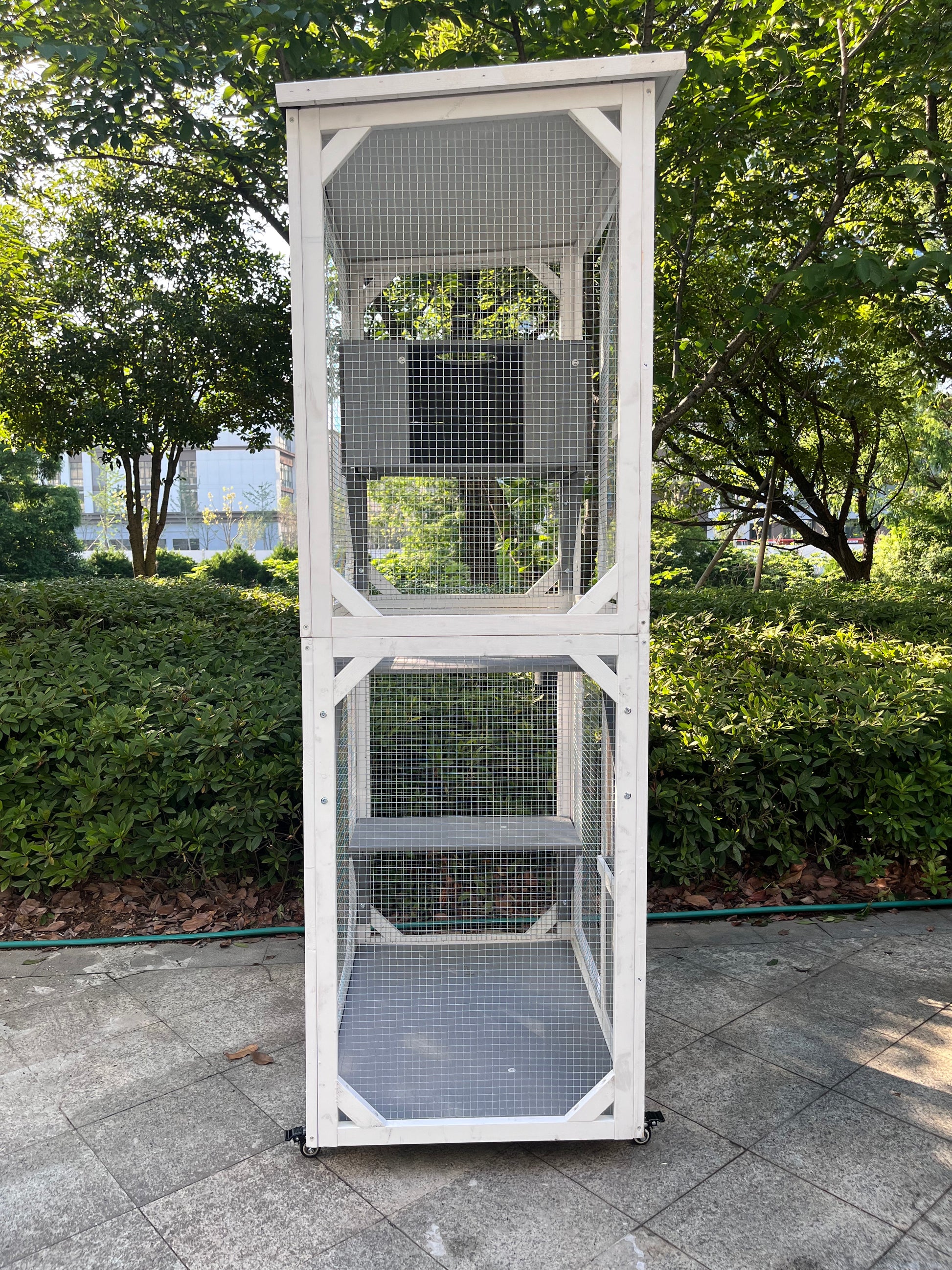 Tall white wooden cat condo with multiple levels and wire mesh enclosure