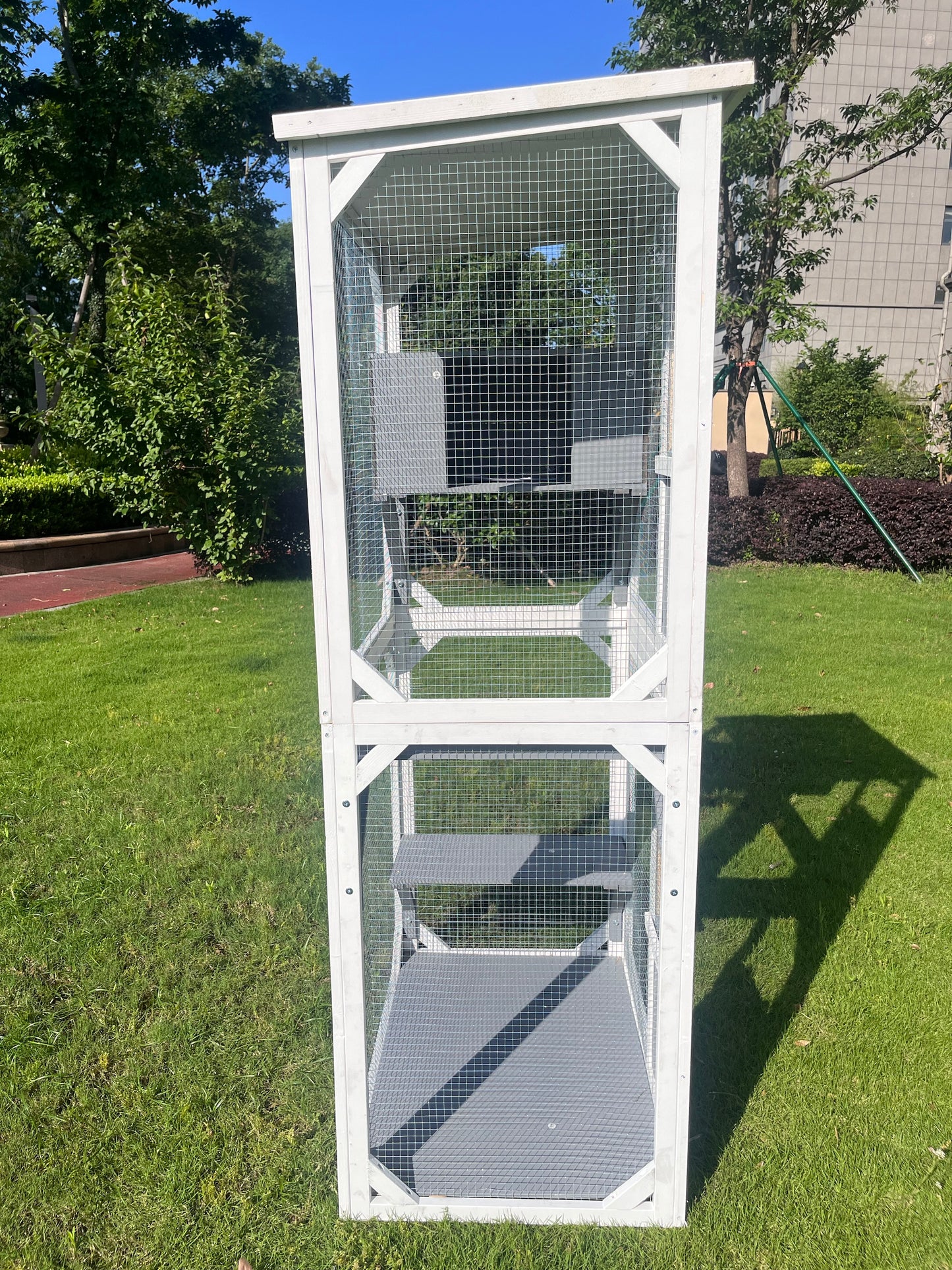 Tall white wooden cat enclosure with multiple levels and wire mesh