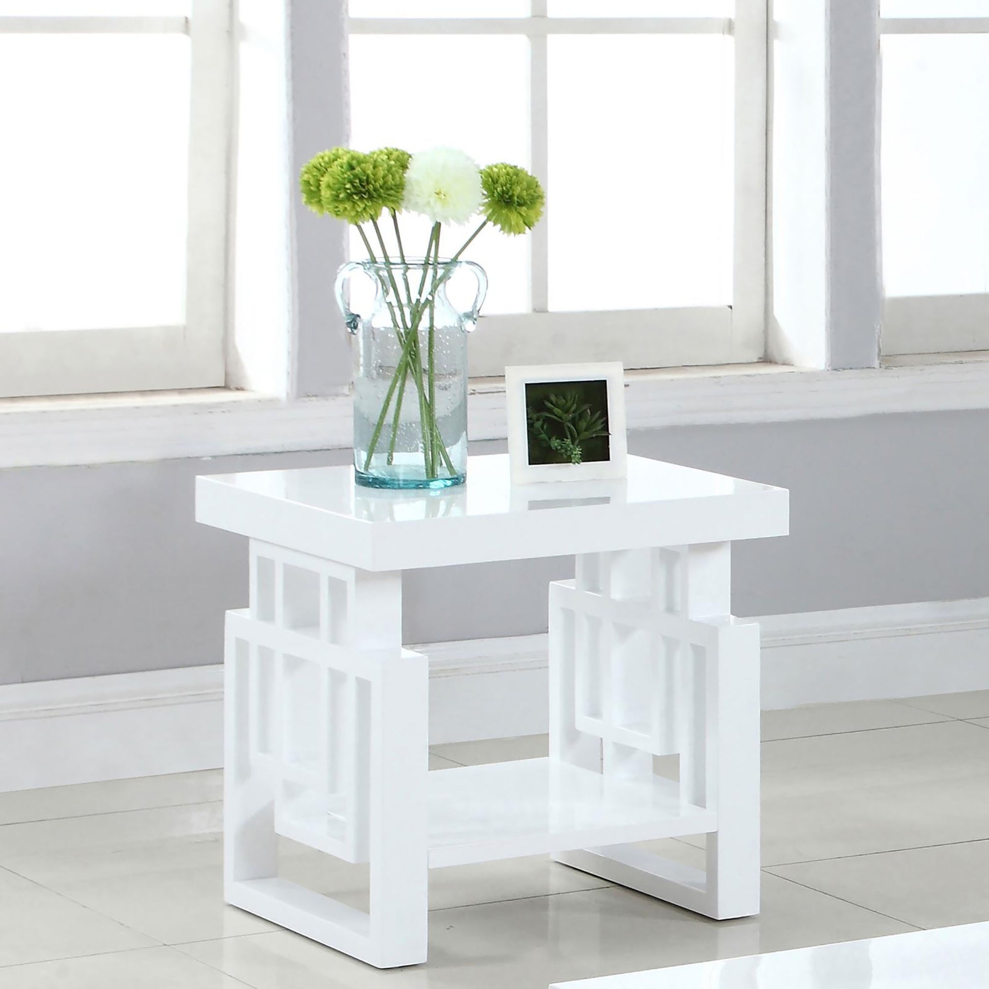 Modern white end table with open geometric shelf and glass vase of greenery