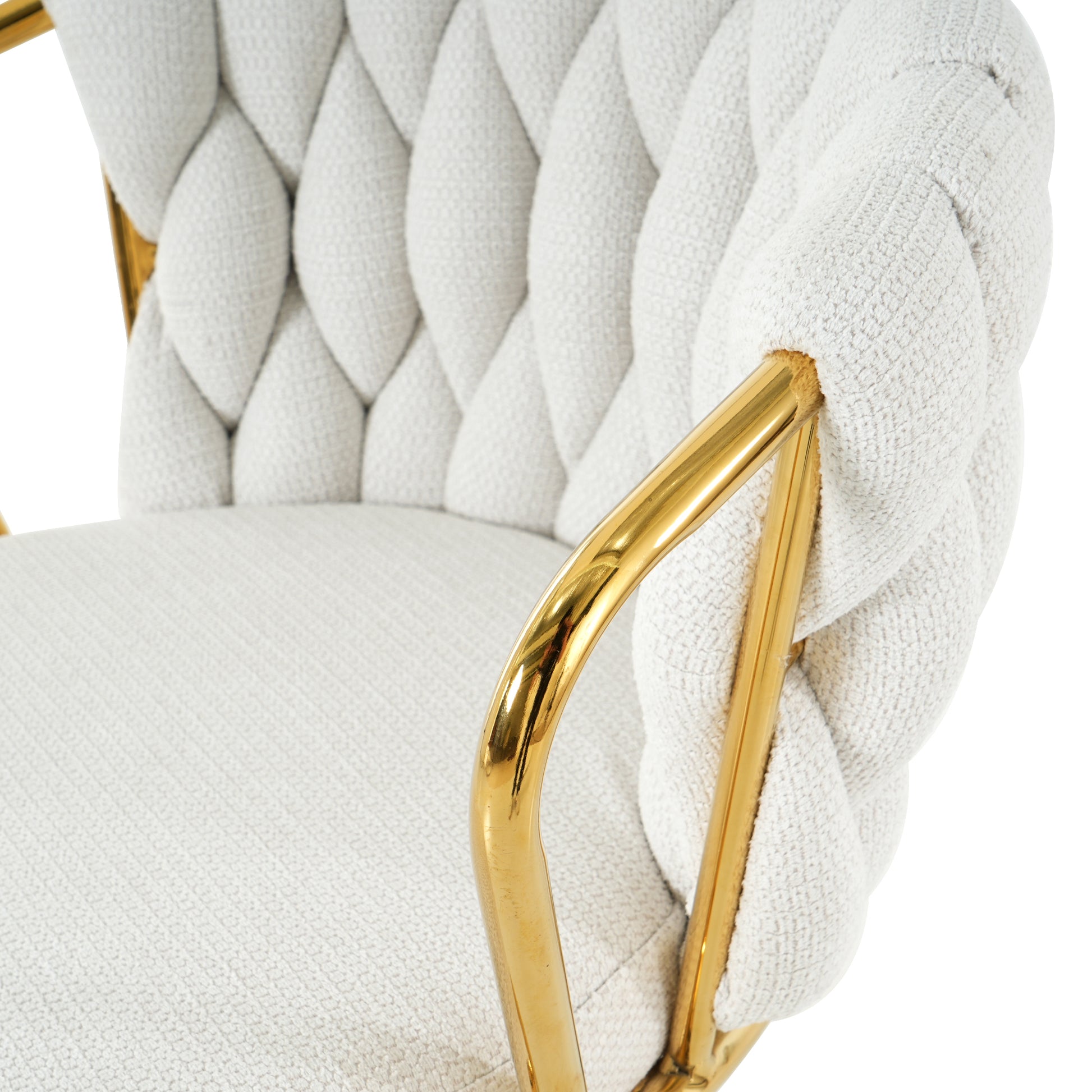 Closeup of a white boucle armchair featuring a thick braided backrest and polished gold frame