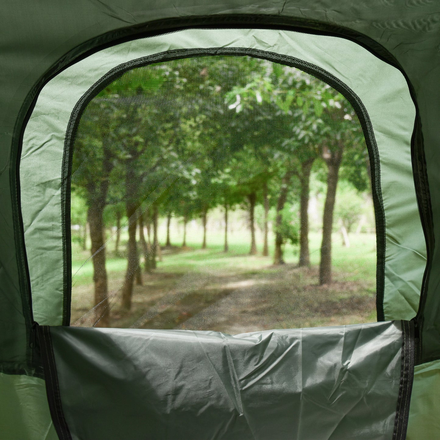 Green camping tent window with mesh screen showing a blurred forest path