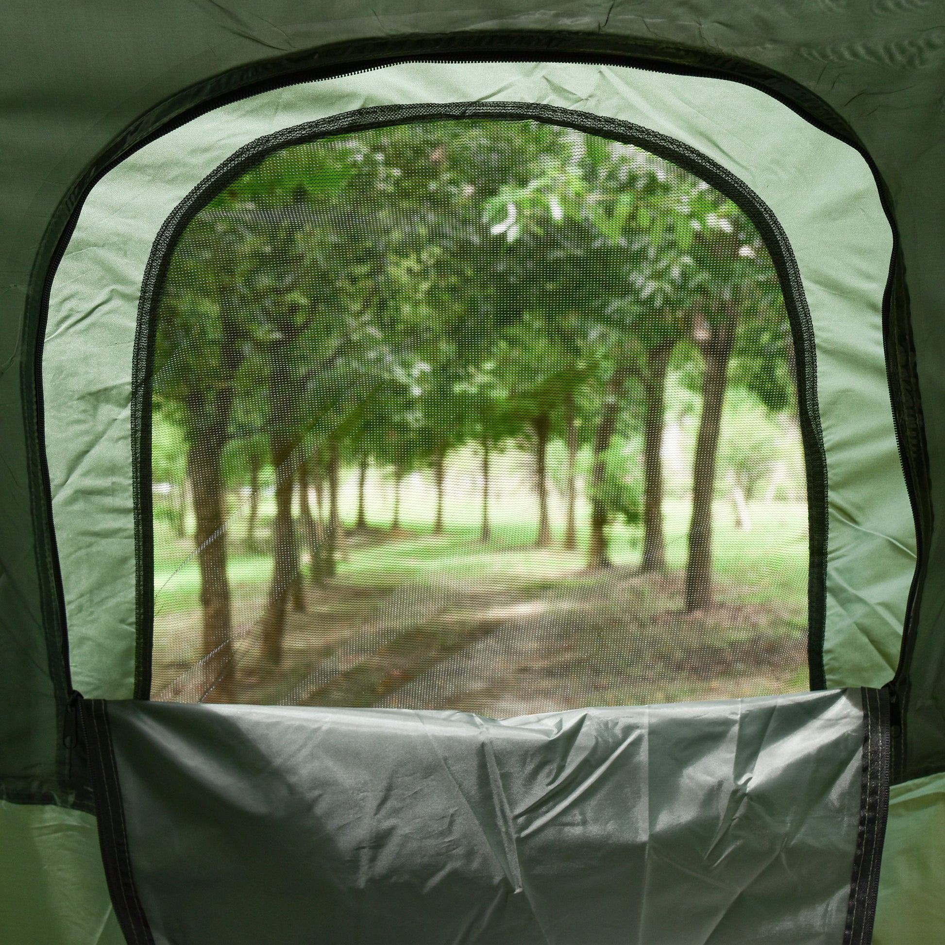 Green camping tent window with mesh screen showing a blurred forest path