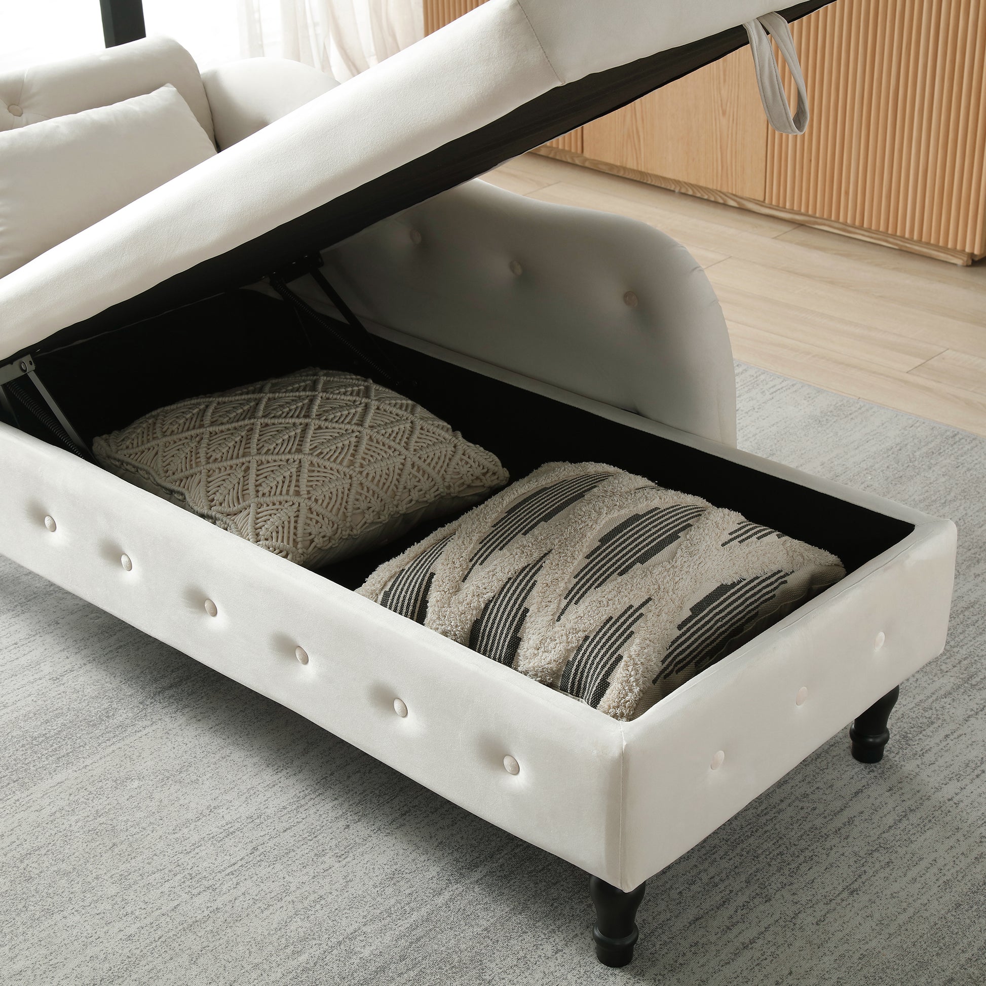 Cream velvet chaise lounge with open storage revealing decorative pillows