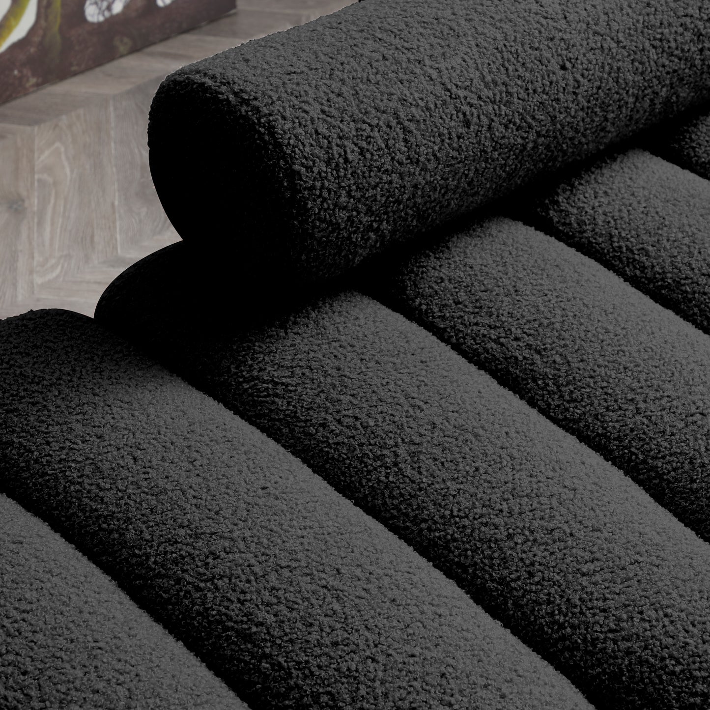 Closeup of a charcoal grey boucle fabric sofa with plush textured cushions