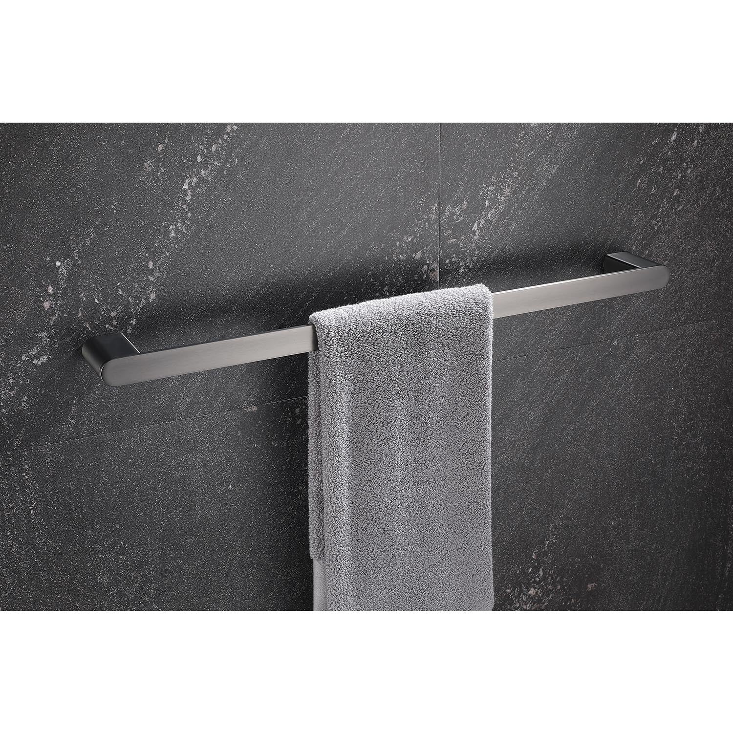 Sleek stainless steel towel bar holding a plush gray towel against a dark granite tiled wall