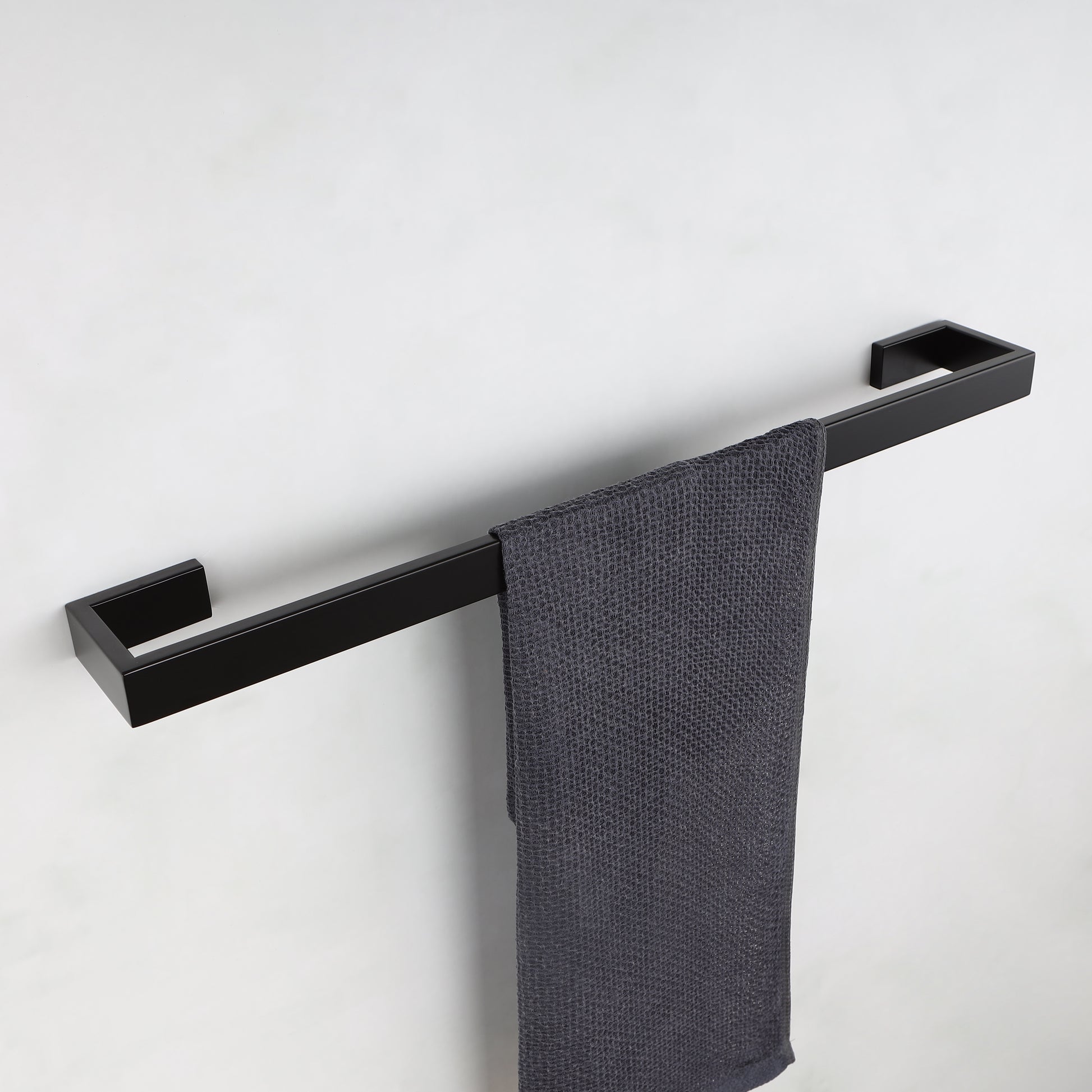 Modern black stainless steel towel bar with a textured charcoal gray hand towel