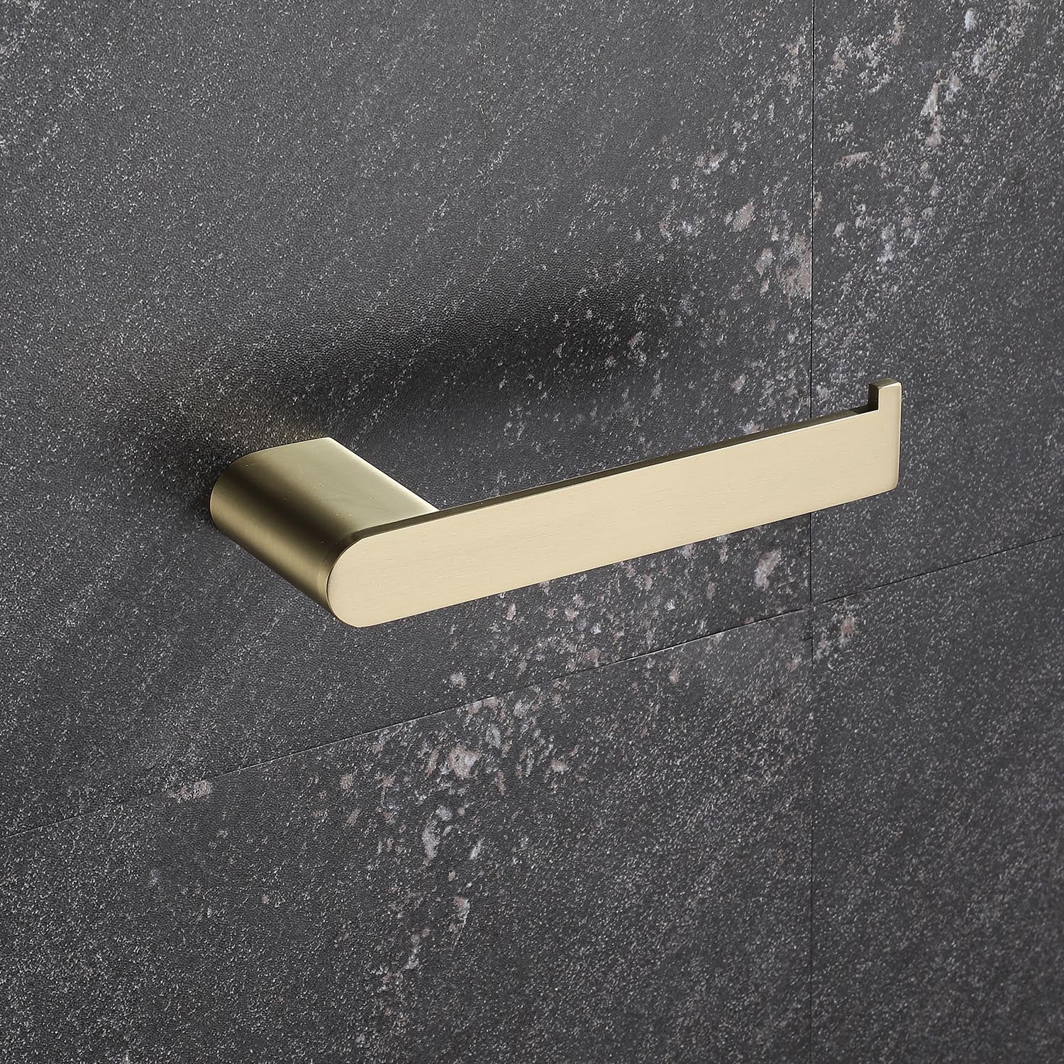 Brushed brass toilet paper holder mounted on a dark textured wall