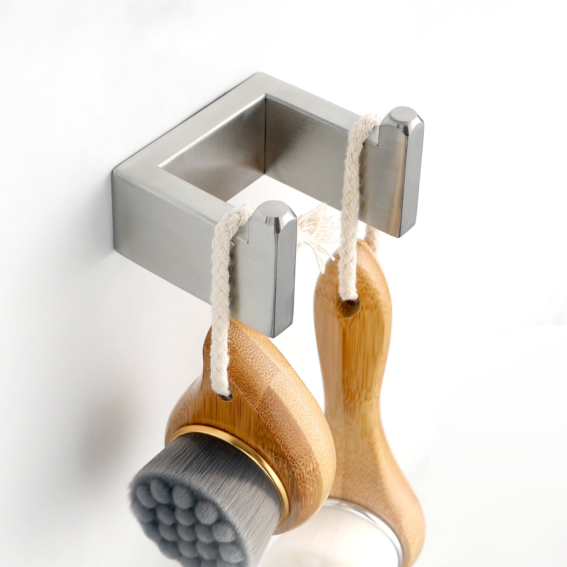 Brushed nickel wall mount holding two bamboo facial cleansing brushes with rope hangers
