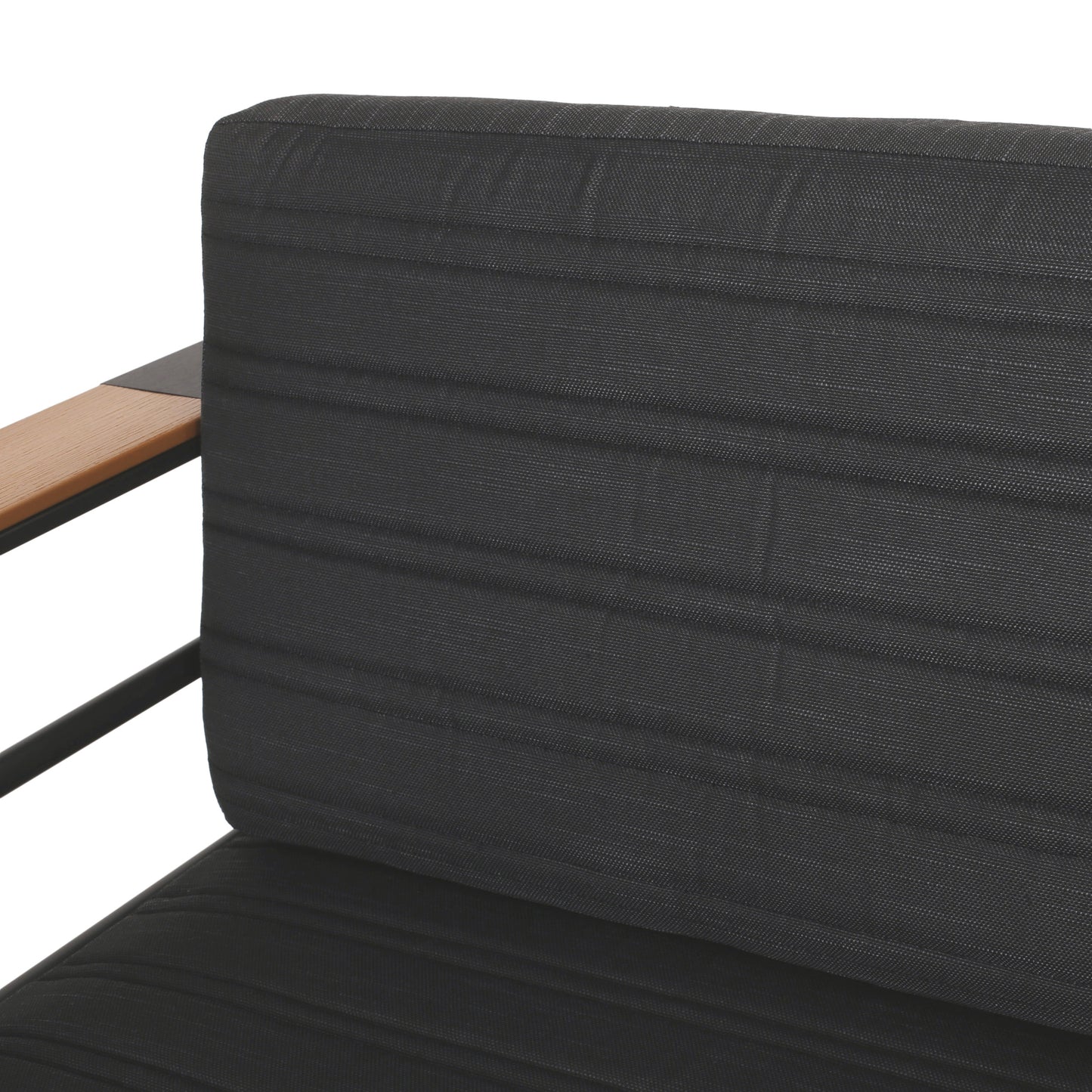 Closeup of a dark grey tufted outdoor sofa cushion with a wooden armrest