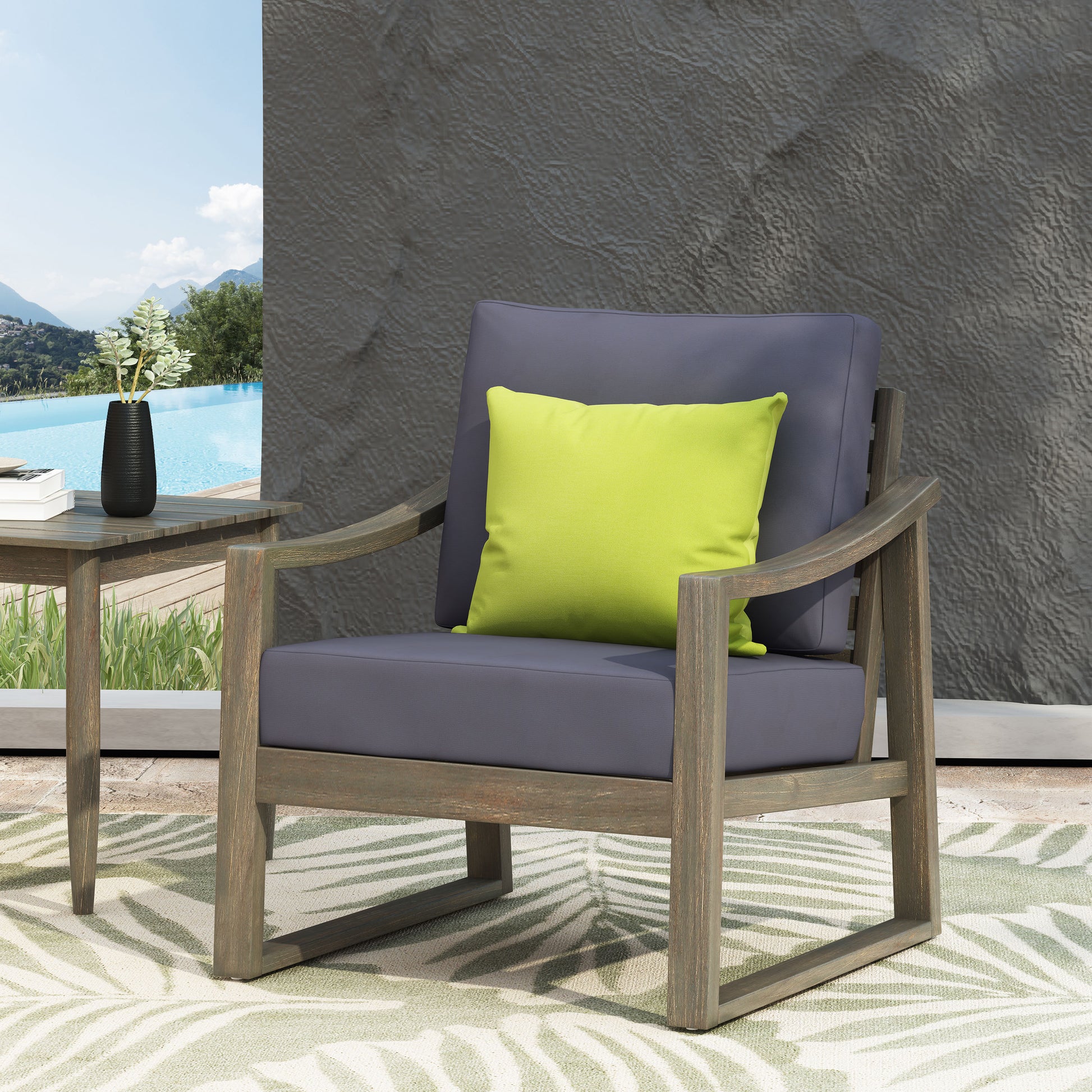 Gray upholstered wooden outdoor armchair with a lime green accent pillow on a patio