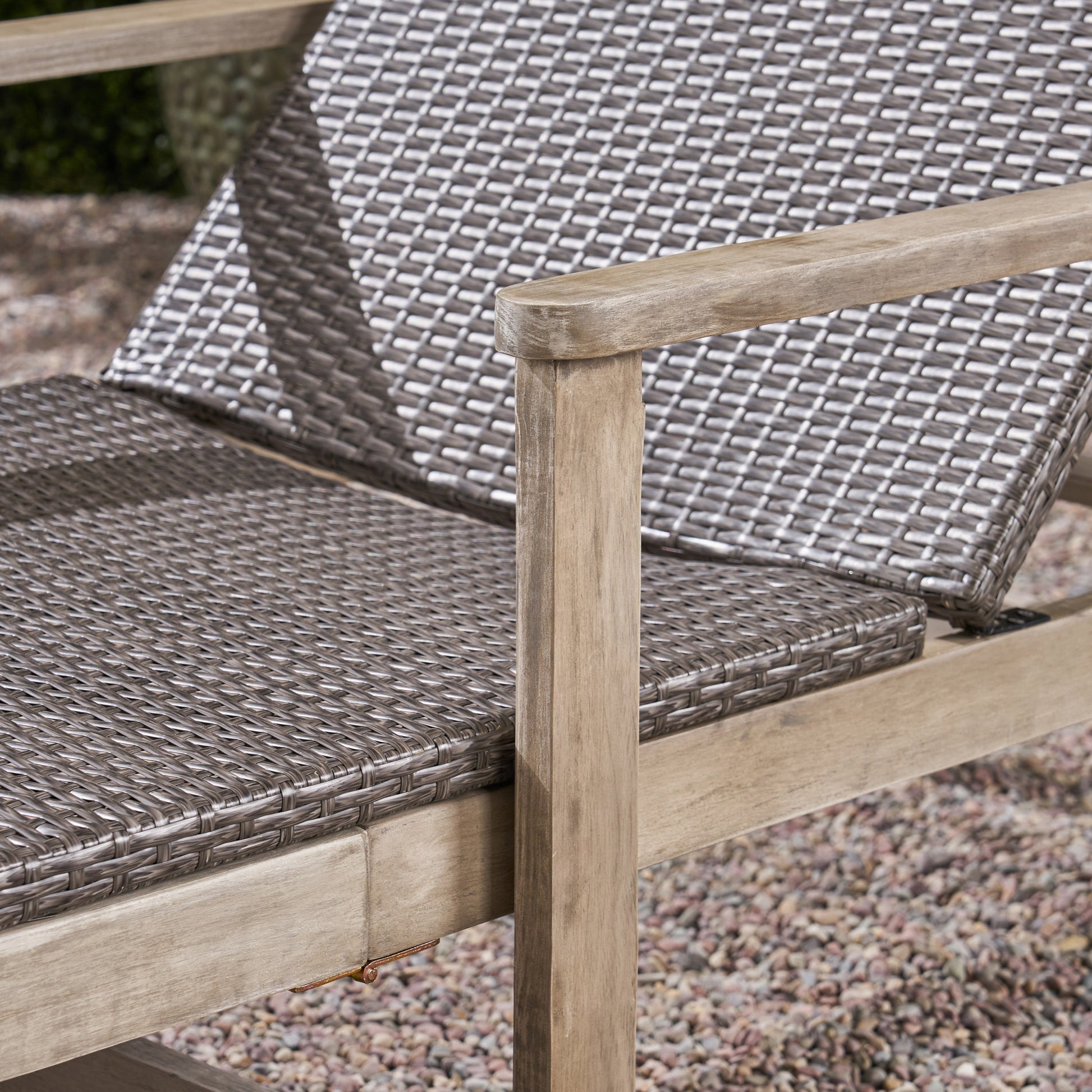 Closeup of a grey wicker outdoor chair with wooden armrests and frame