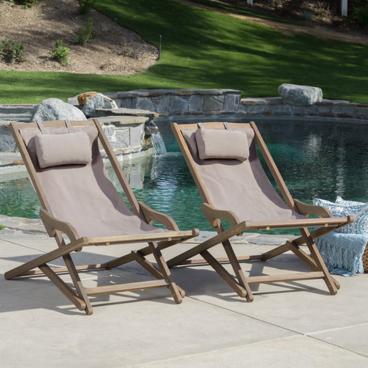 Two taupe canvas sling chairs with wooden frames sit poolside