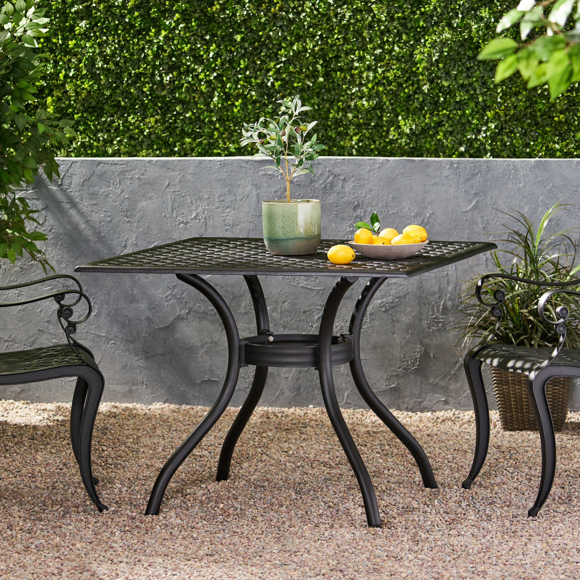 Black metal square patio table with a decorative grid top and ornate legs perfect for outdoor dining