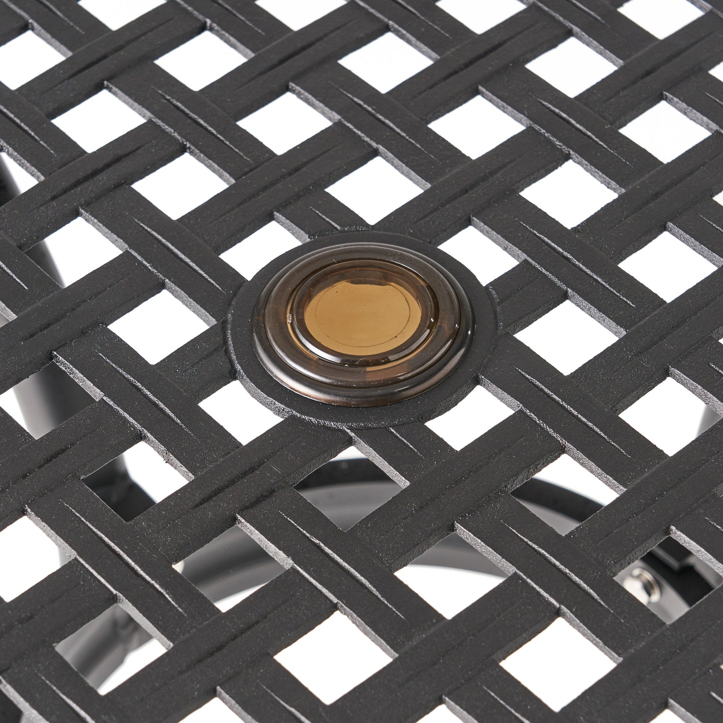 Closeup of black metal table surface with woven design and amber glass accent