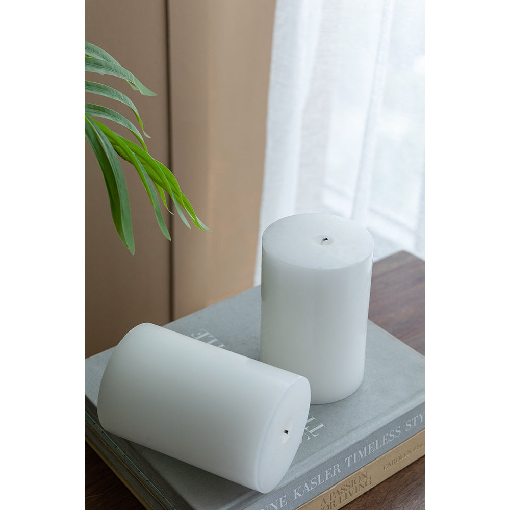 Two minimalist white pillar candles on a book evoking modern home decor