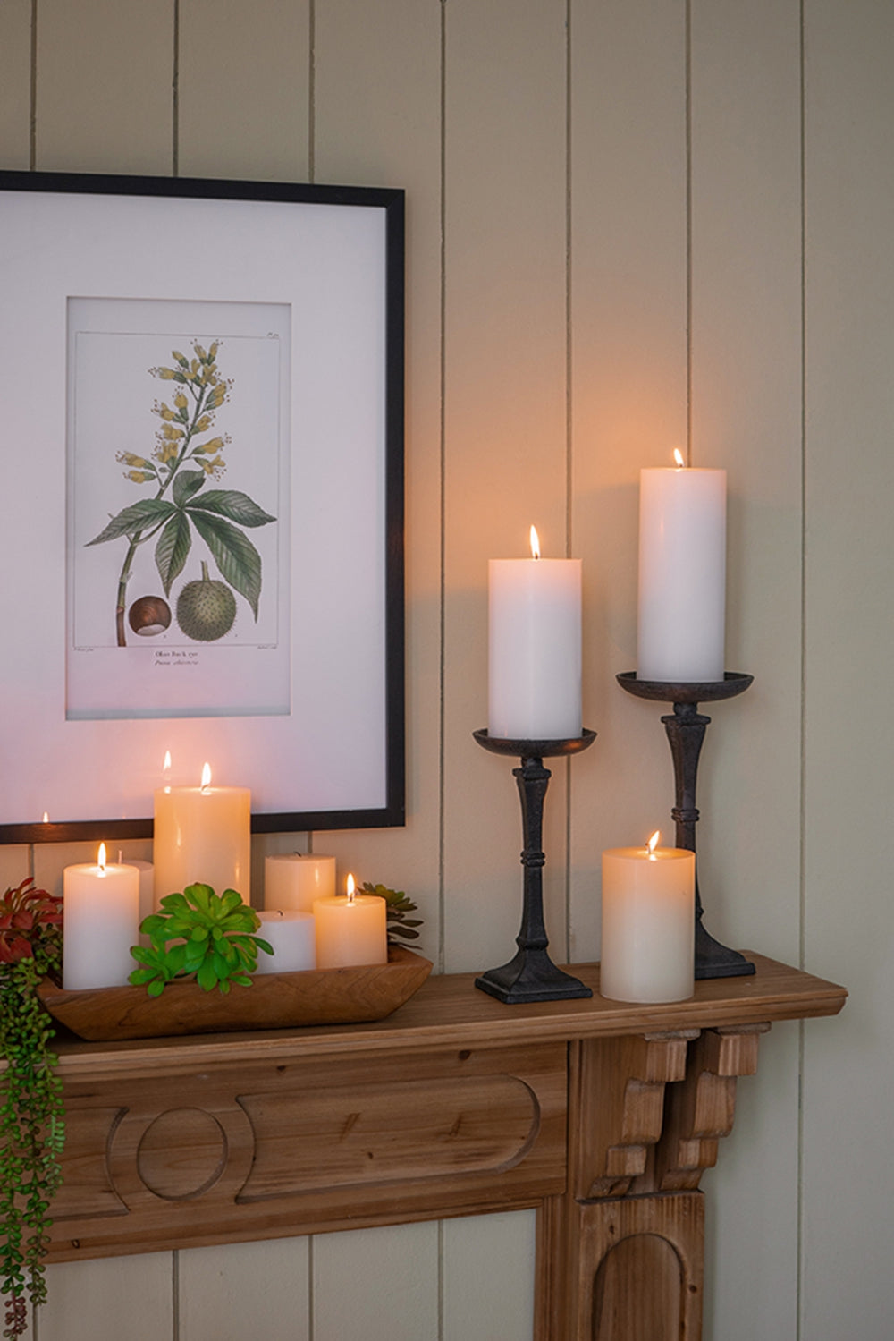 Set of white pillar candles on a rustic wooden shelf with decorative accents