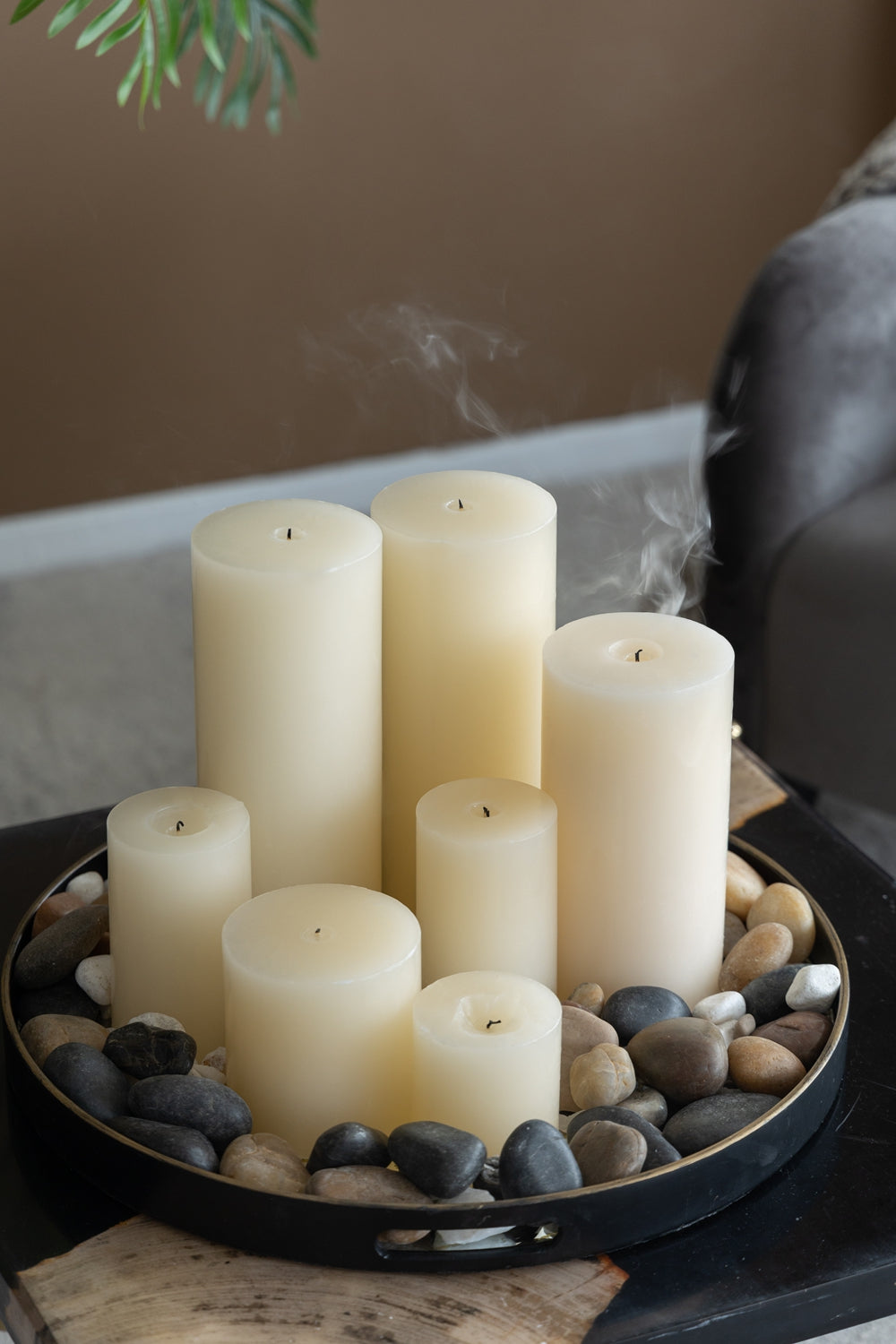 Set of cream pillar candles on a decorative tray with river stones for ambient lighting