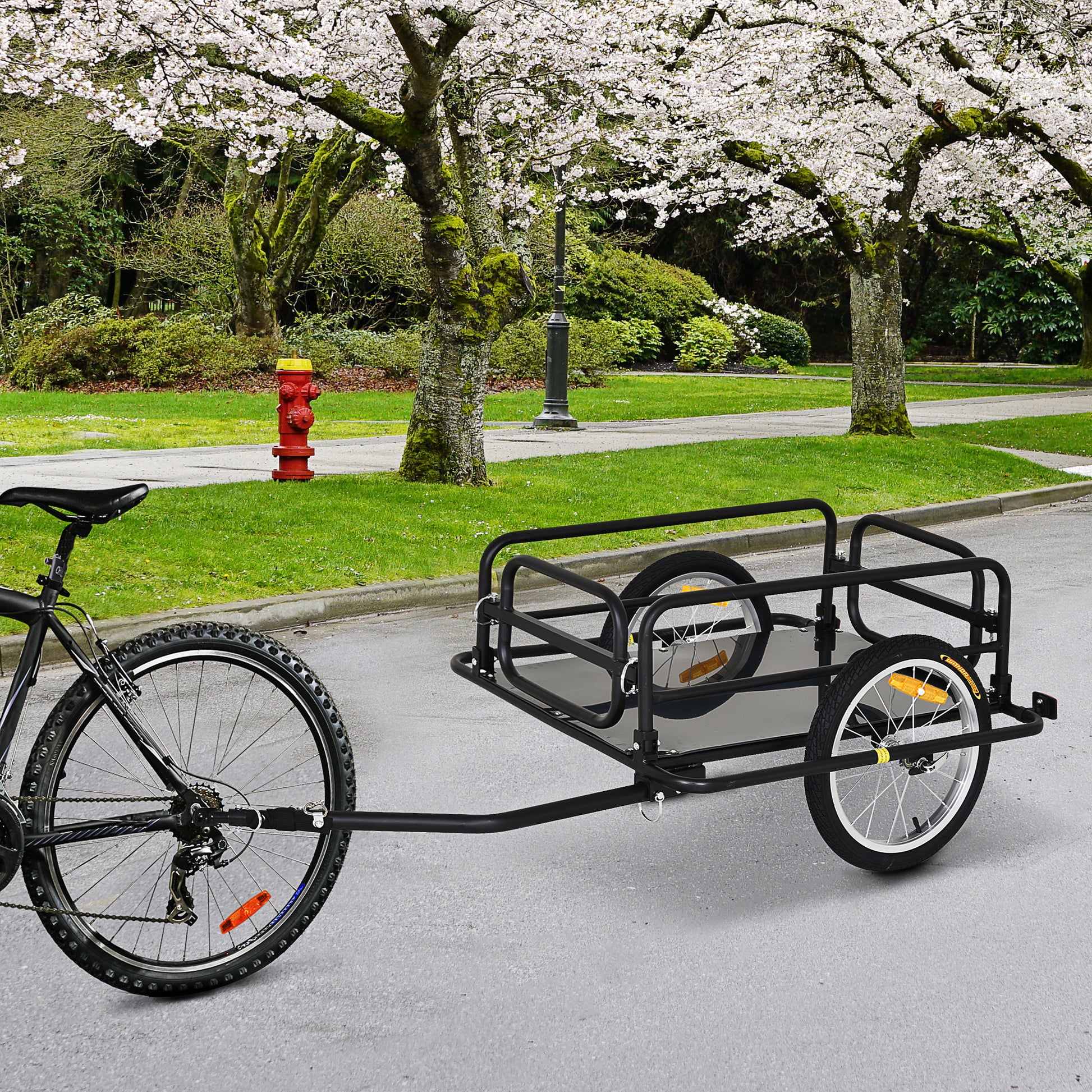 Black metal bicycle cargo trailer with two wheels and tow bar attached to a mountain bike
