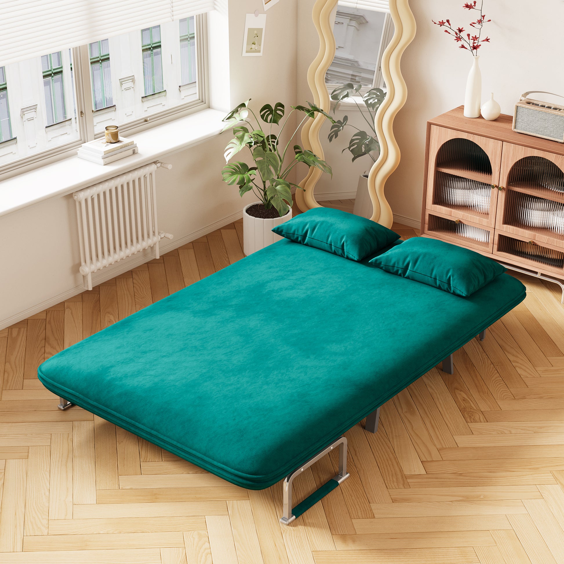 Teal velvet sofa bed with two pillows featuring a modern design and metal legs
