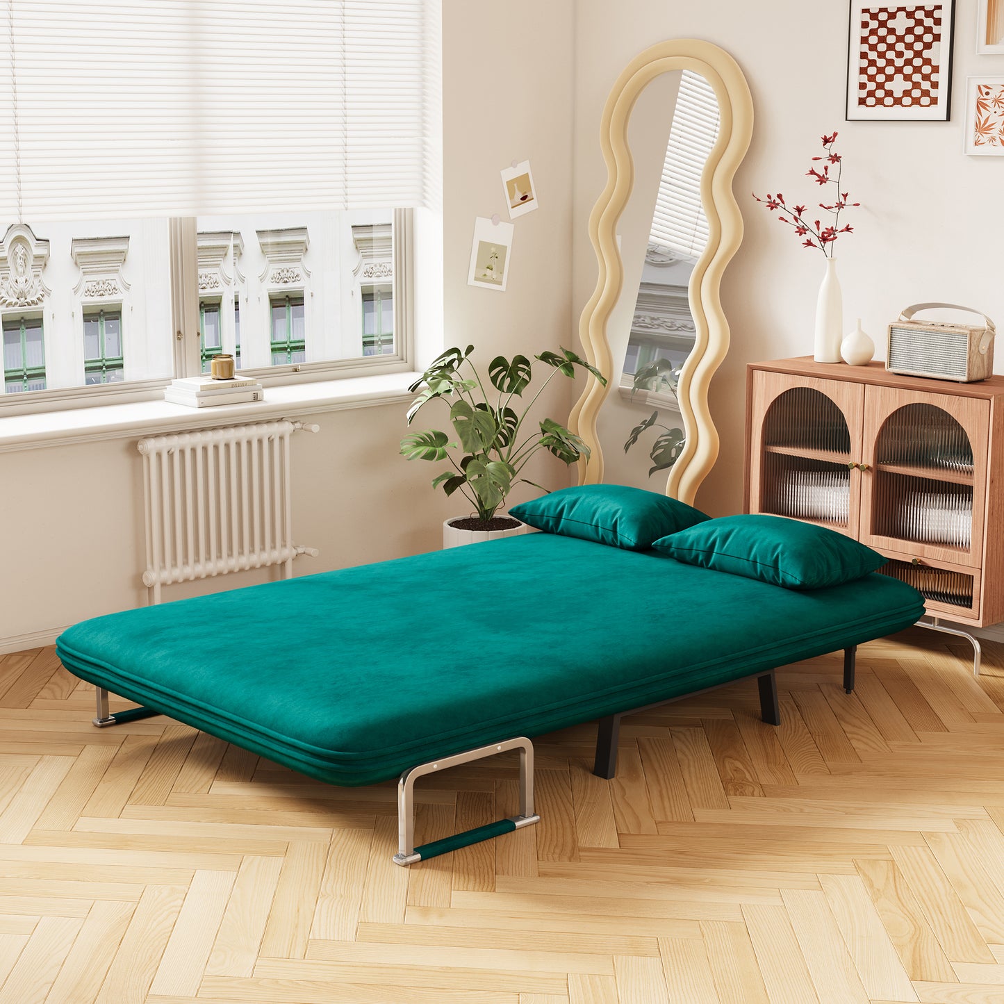 Teal velvet convertible sofa bed with two green pillows metal legs and a footrest