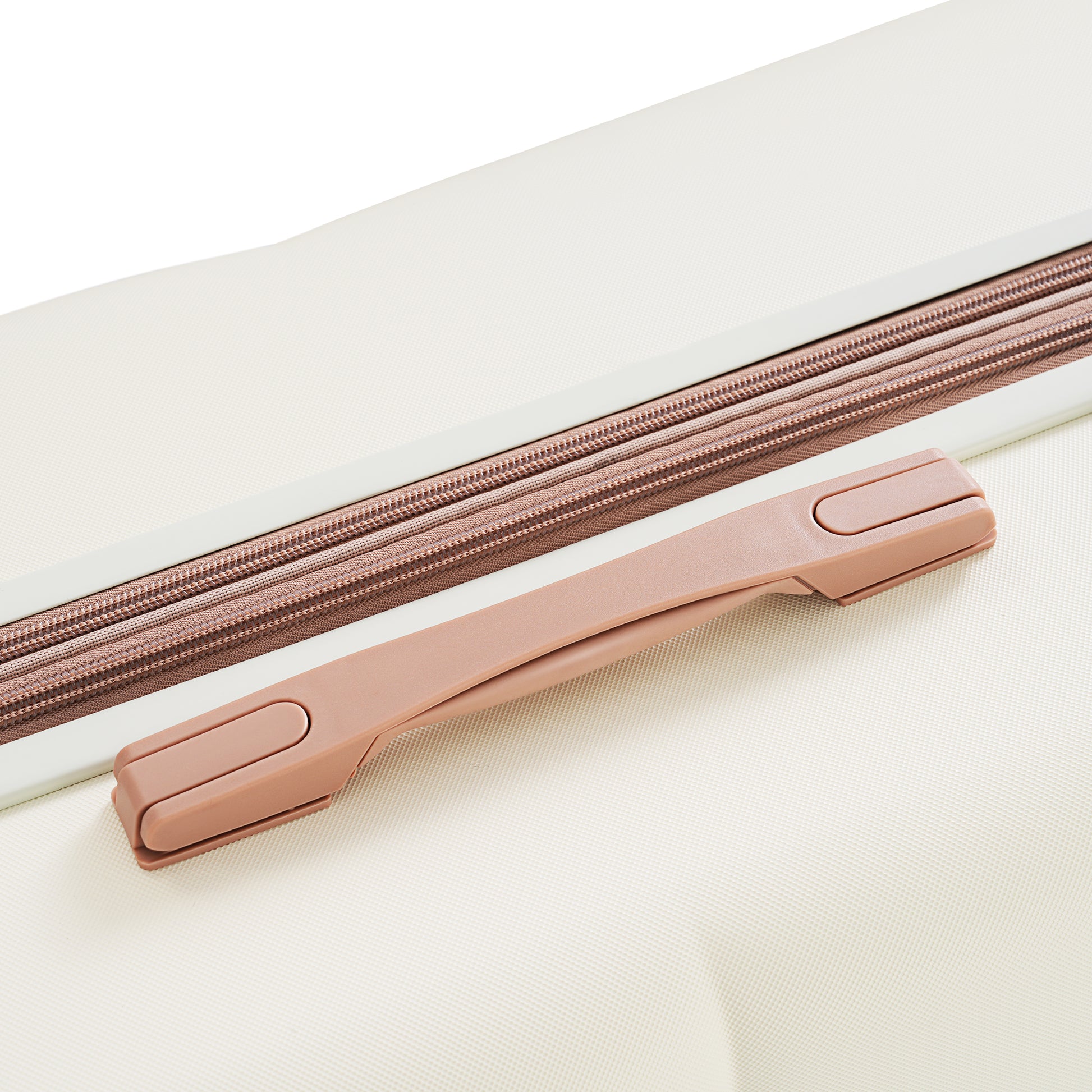 Closeup of a textured cream suitcase with a rose gold zipper and handle detail