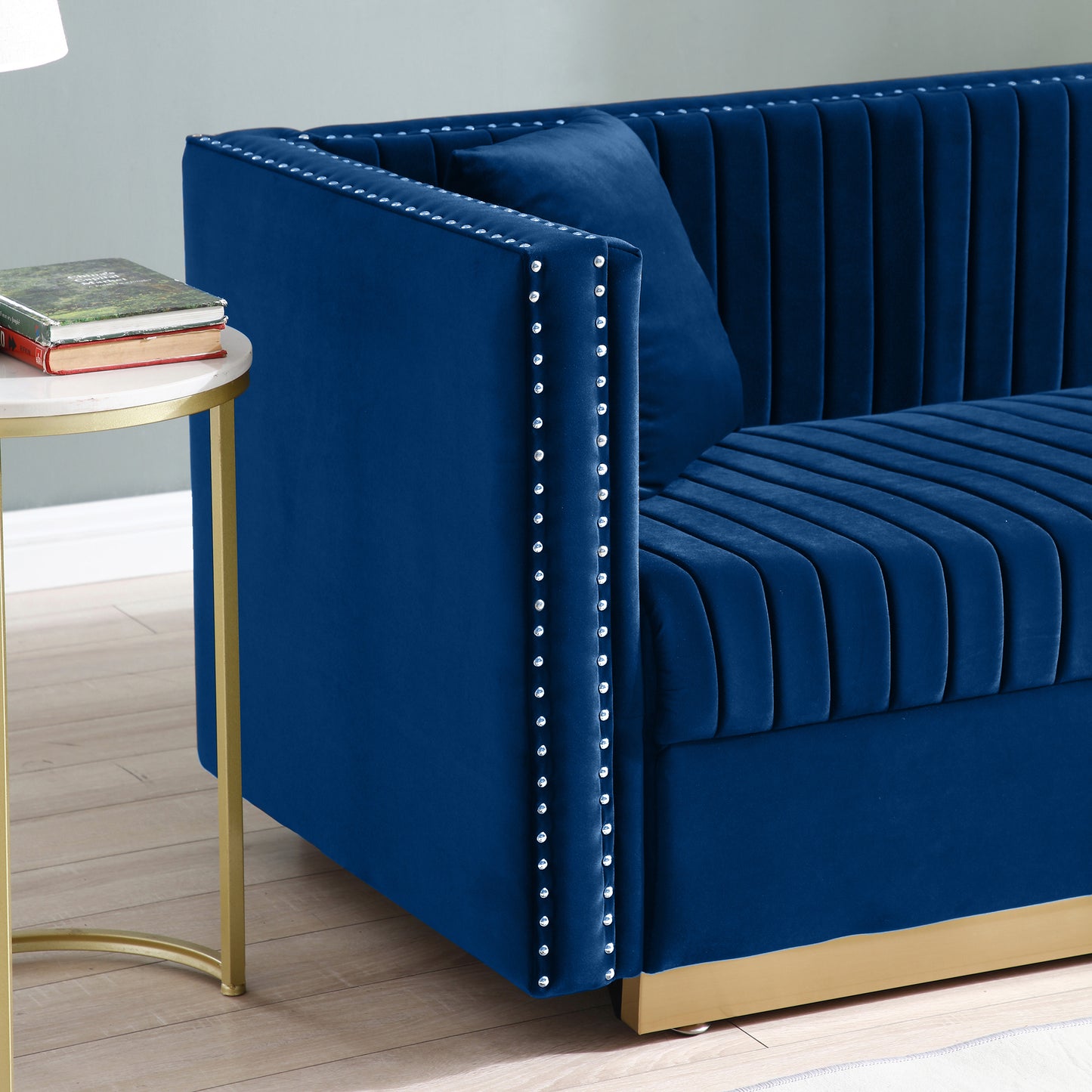 Deep blue velvet sofa with channel tufting and silver nailhead trim details