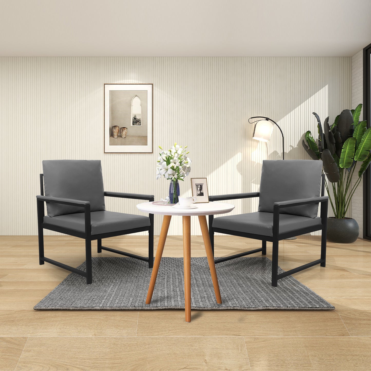 Two modern gray armchairs with black metal frames beside a small round white table